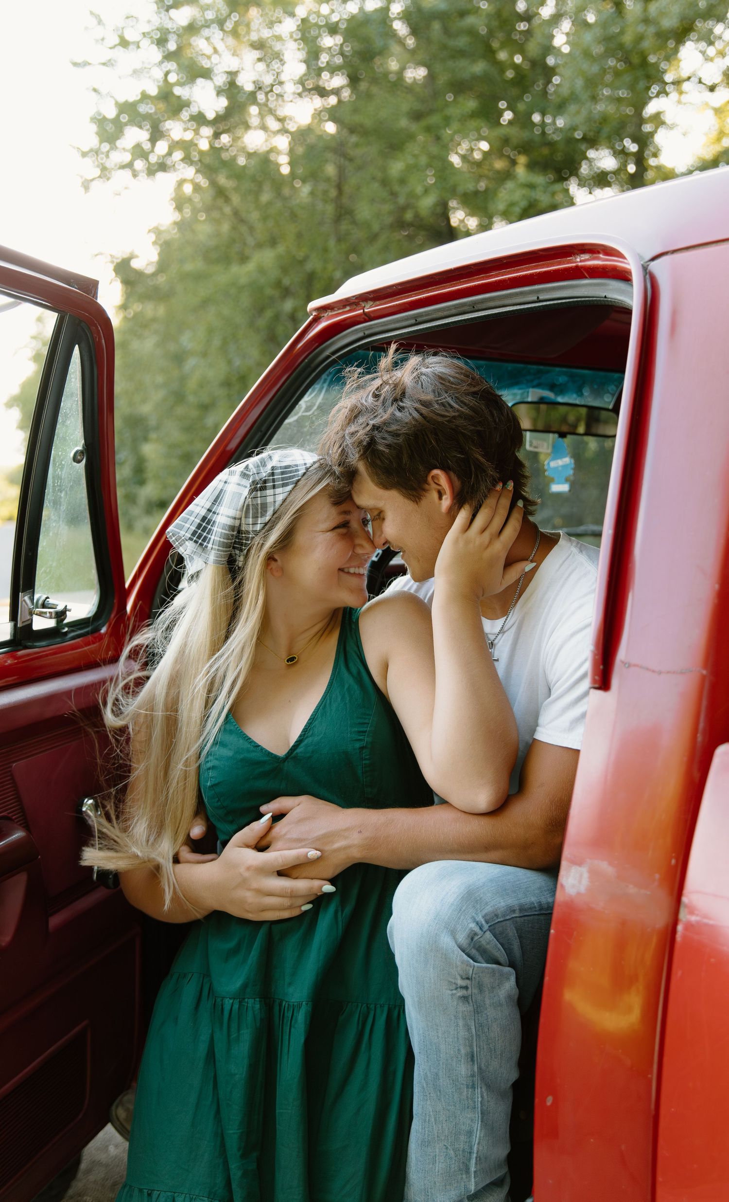 A romantic couple shares an intimate moment inside a vintage red pickup truck on a sunny summer day in Northwest Ohio.