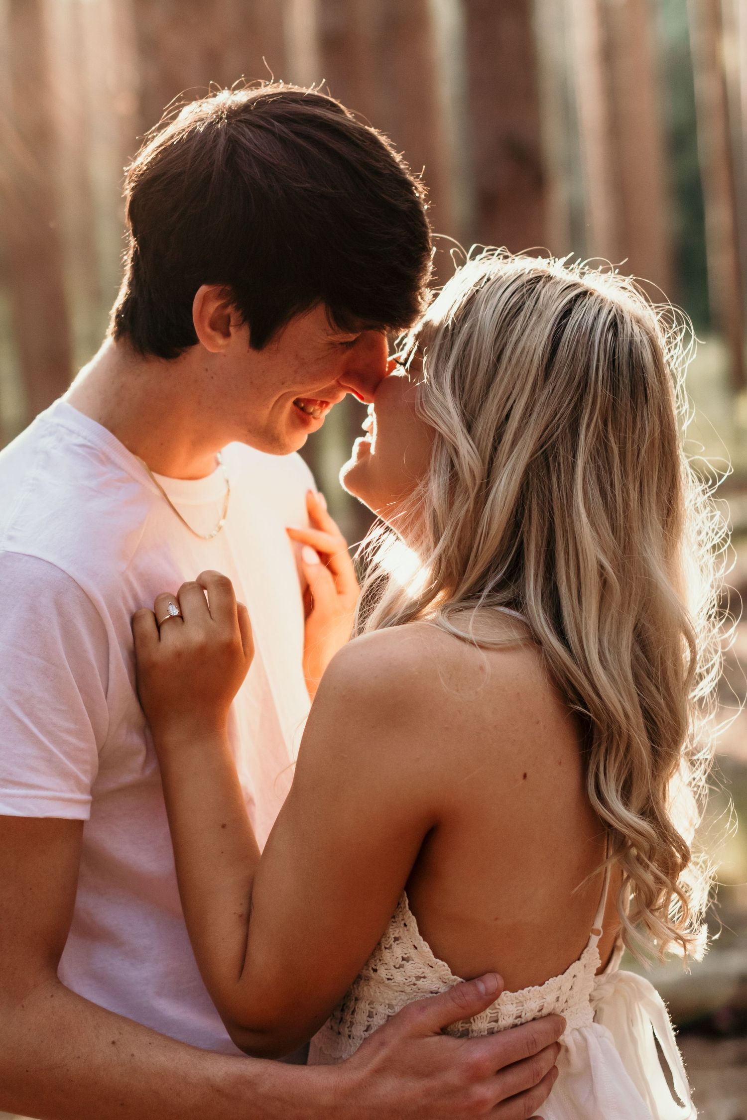 An intimate moment shared between a couple in a sunlit forest.
