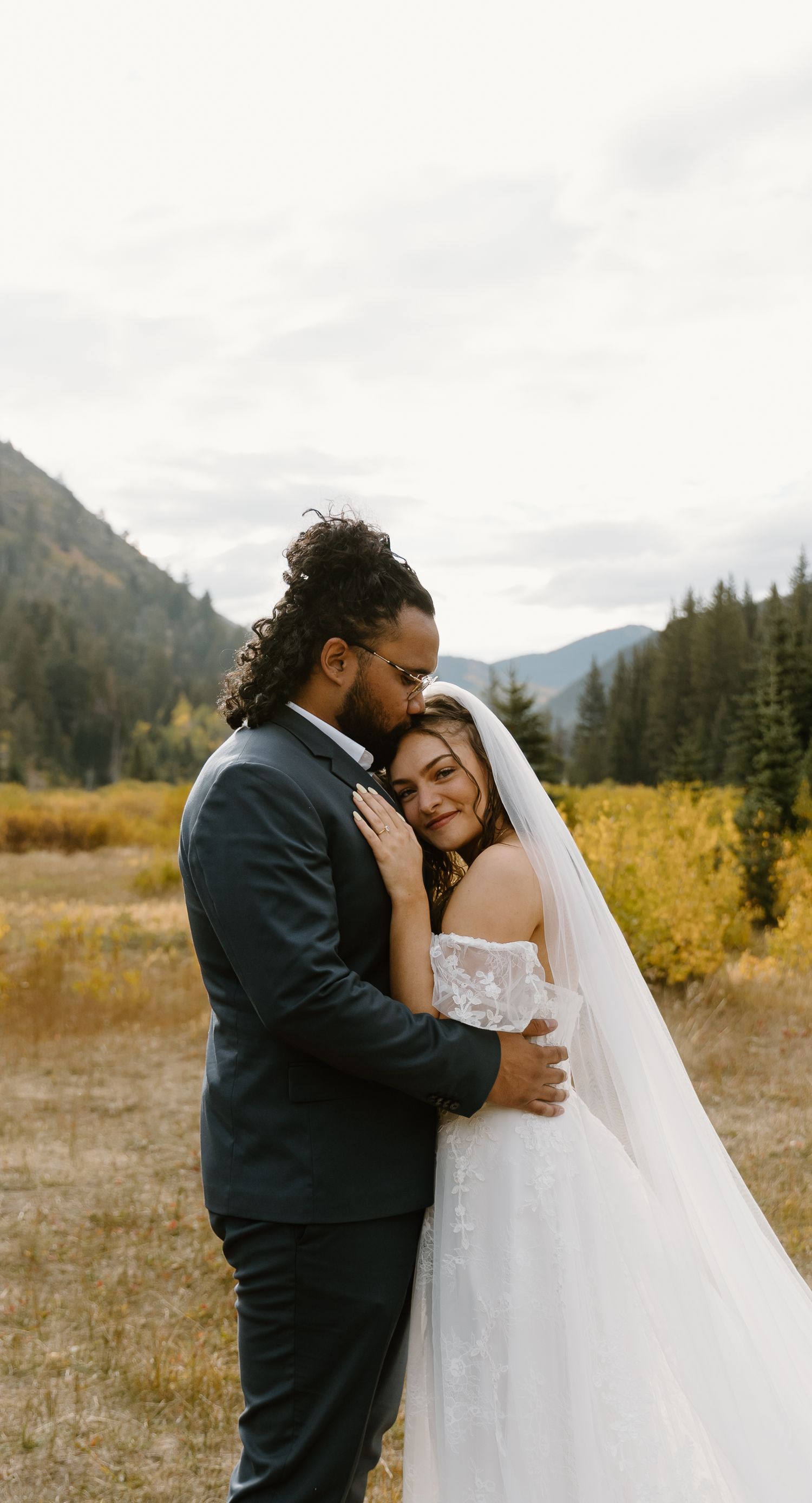 Intimate wedding moments captured in a mountain meadow with evergreen trees and natural scenery.