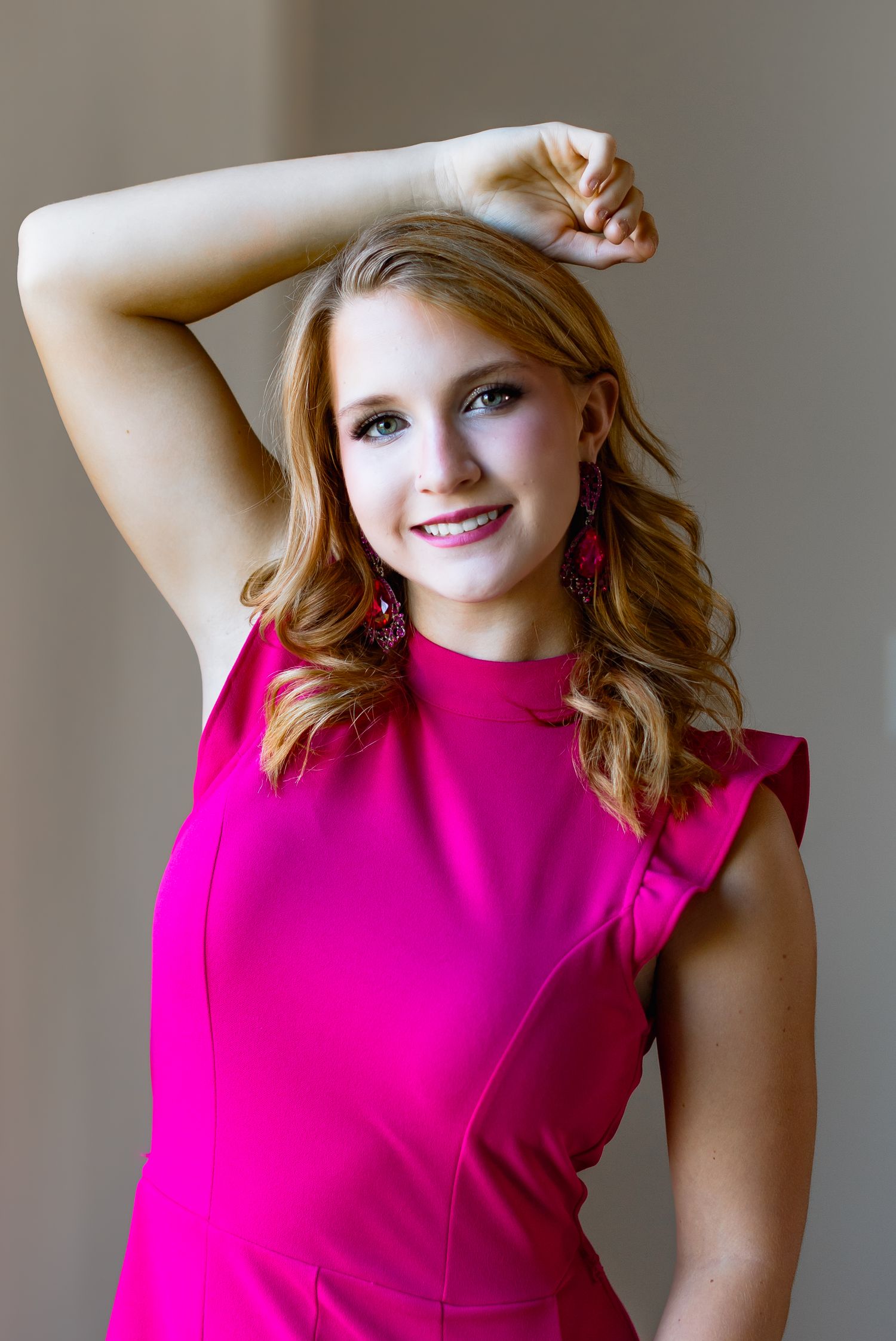 Studio portrait featuring a bright fuchsia dress with ruffle details.