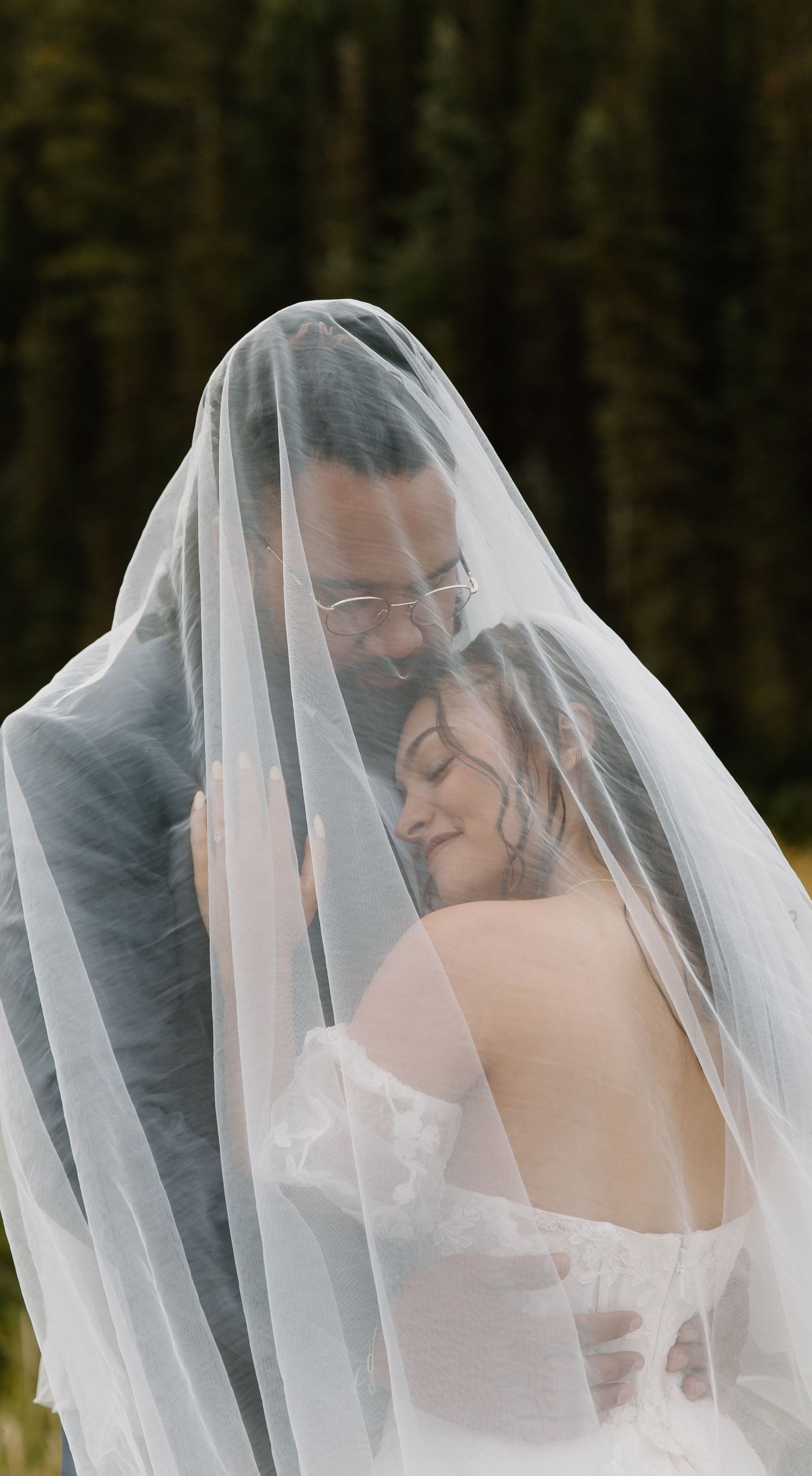 A romantic wedding scene with a couple sharing a tender moment under a delicate white veil.