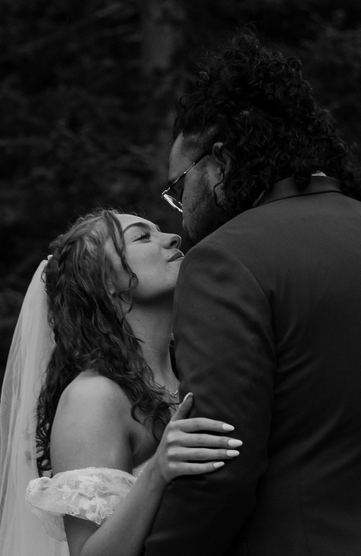 A black and white photo series showing a romantic wedding kiss sequence between a bride and groom.