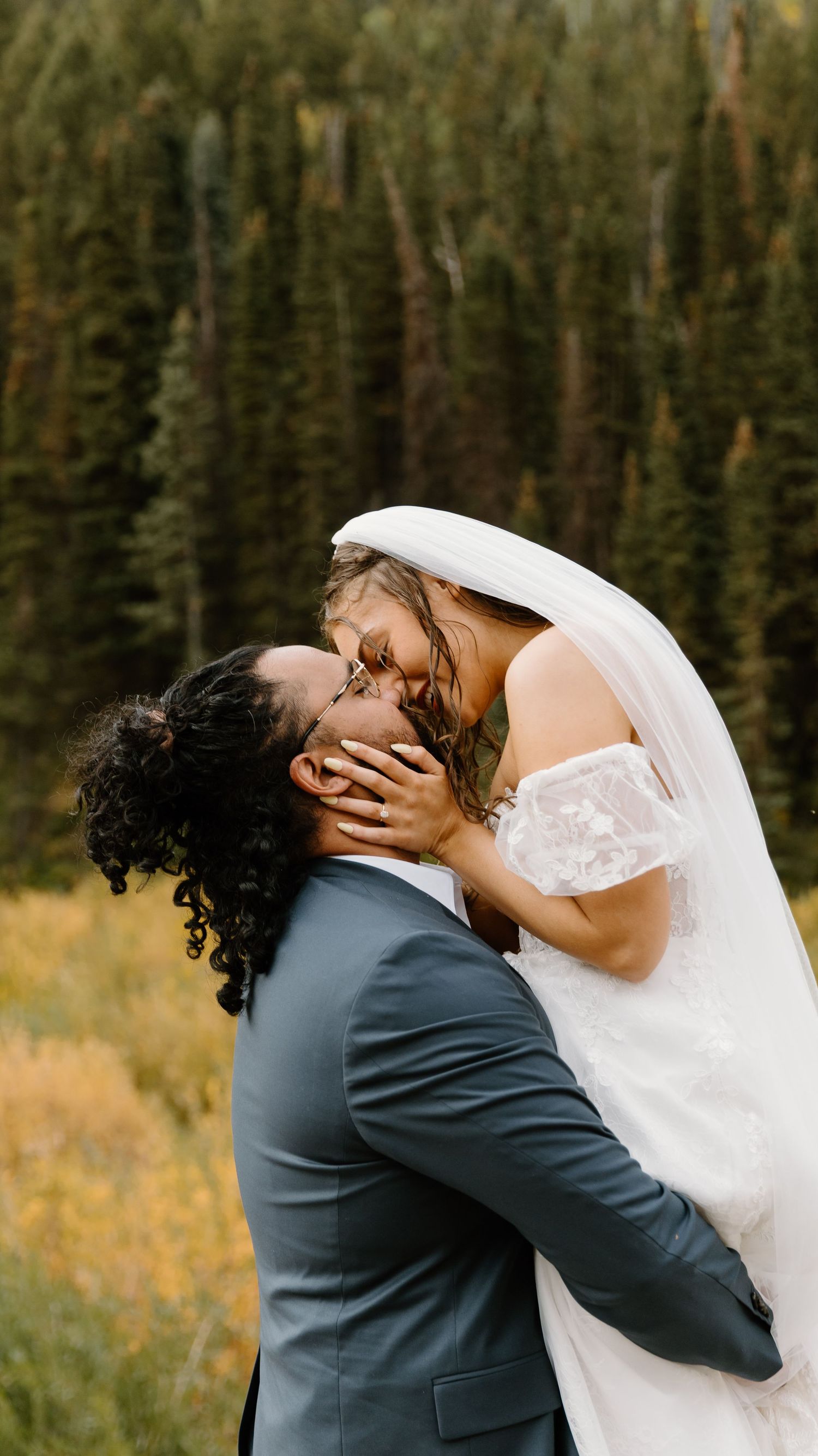 Intimate wedding photos captured in a mountain setting with evergreen trees and autumn foliage.