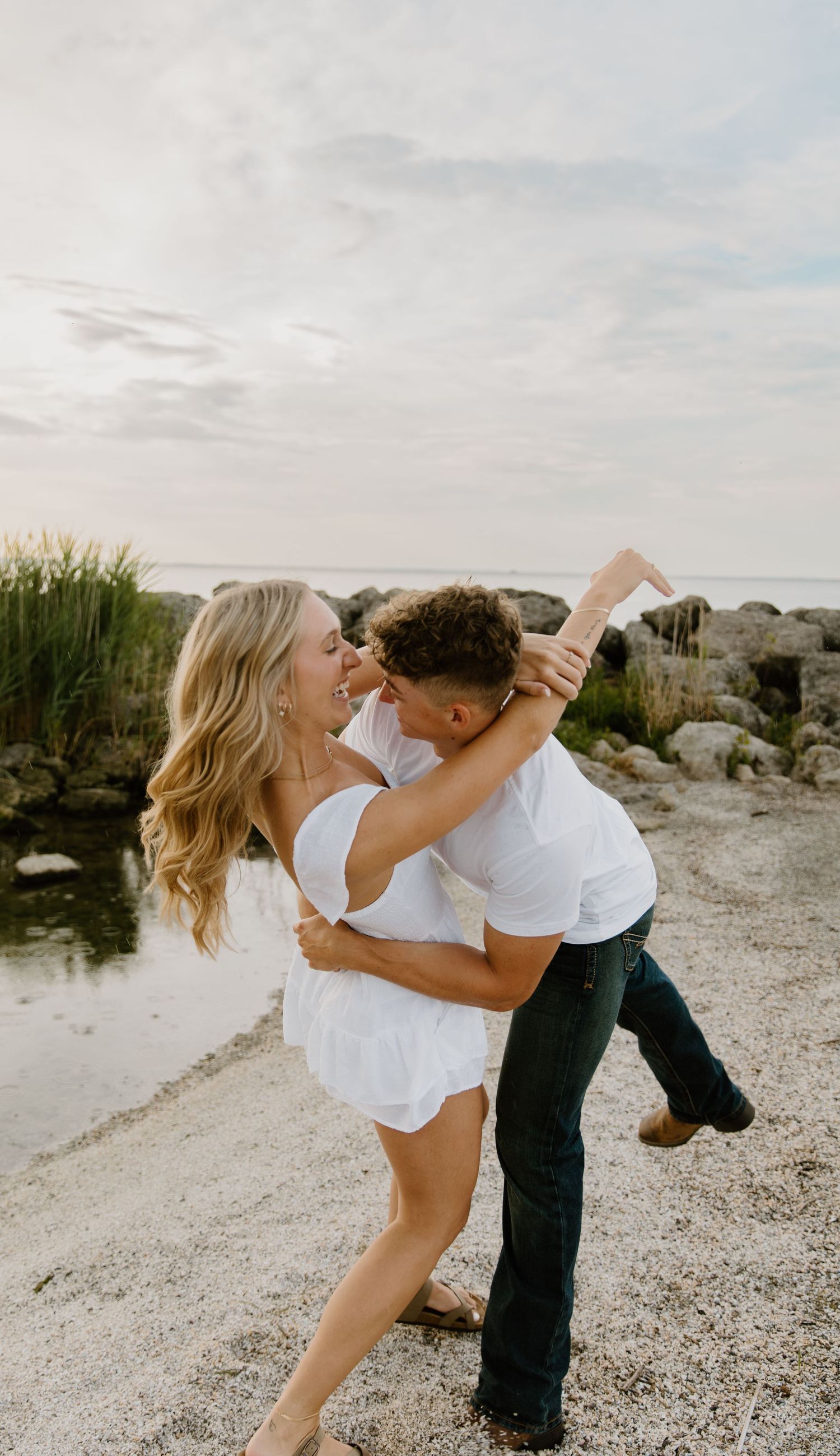 A romantic dance sequence on a rocky beach showing a graceful dip pose at sunset at maumee bay in ohio.