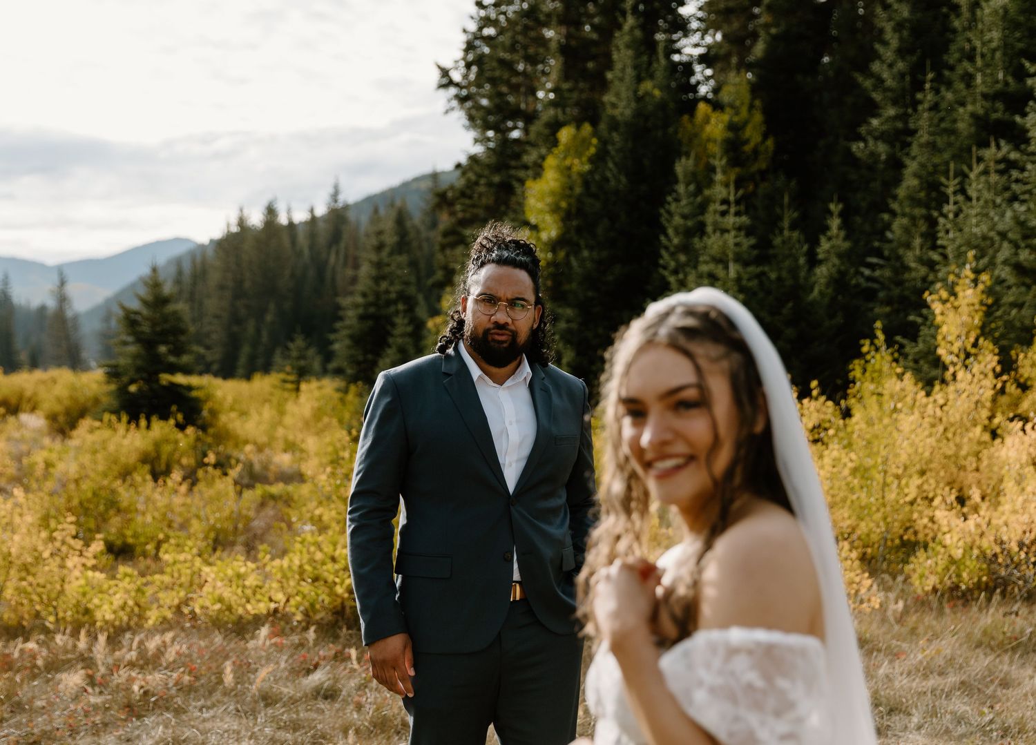 A joyful wedding moment photographed in a scenic mountain setting with fall colors.