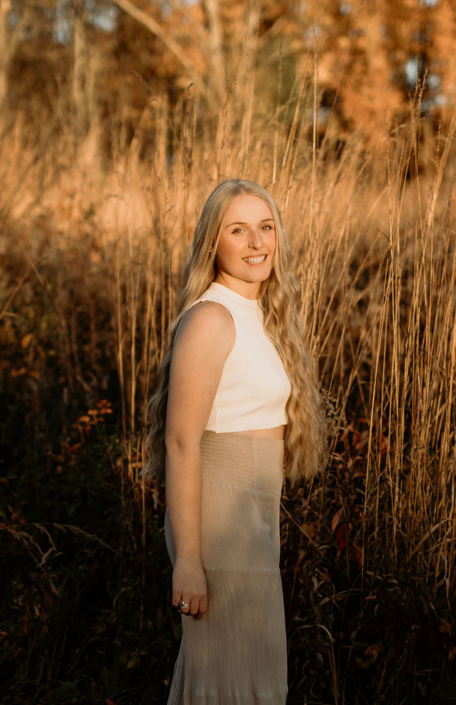 Portrait in golden hour light with tall grass and warm autumn colors in the background.
