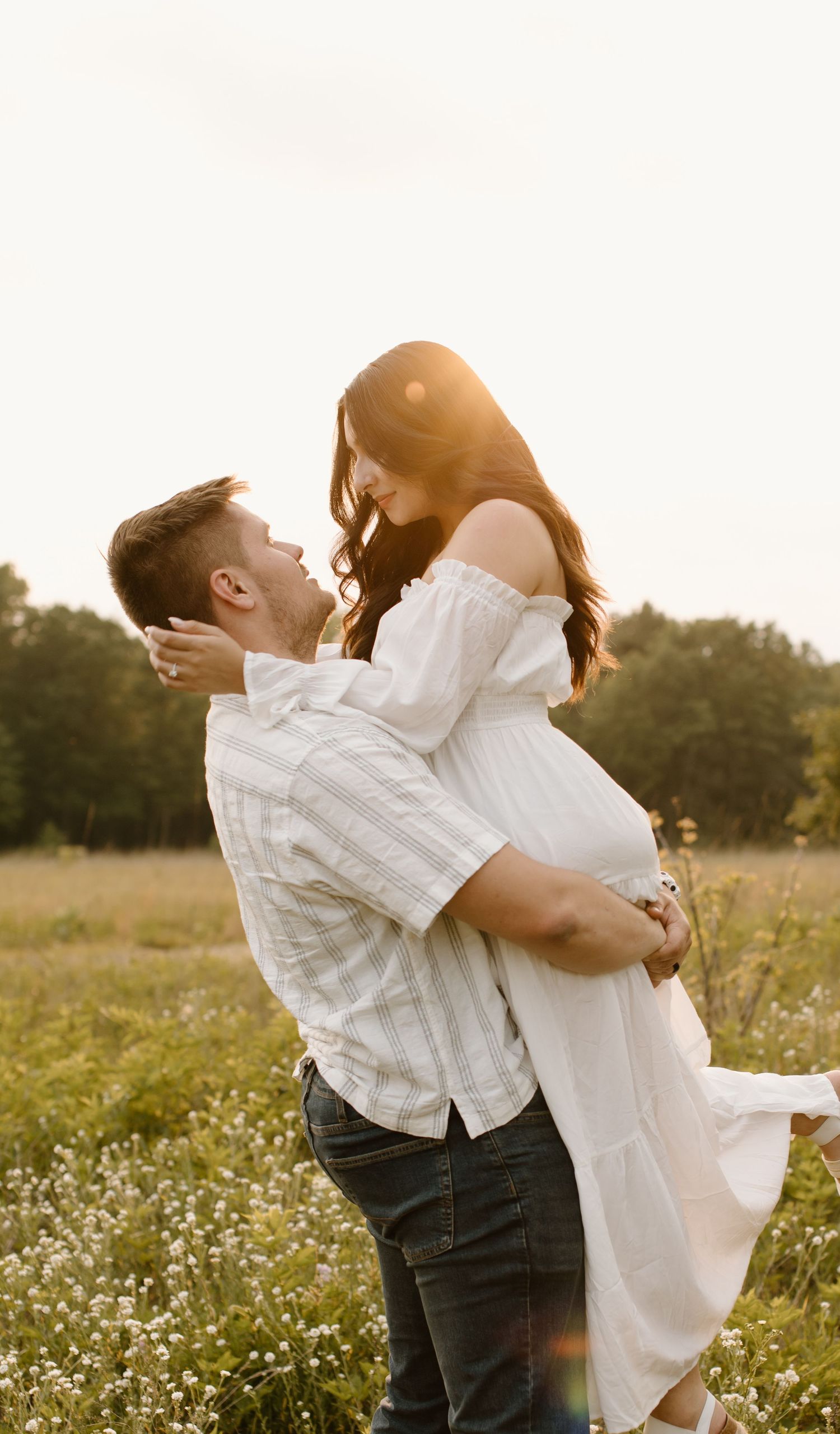 A romantic couple embraces in a sunlit wildflower meadow during golden hour, creating an ethereal moment.