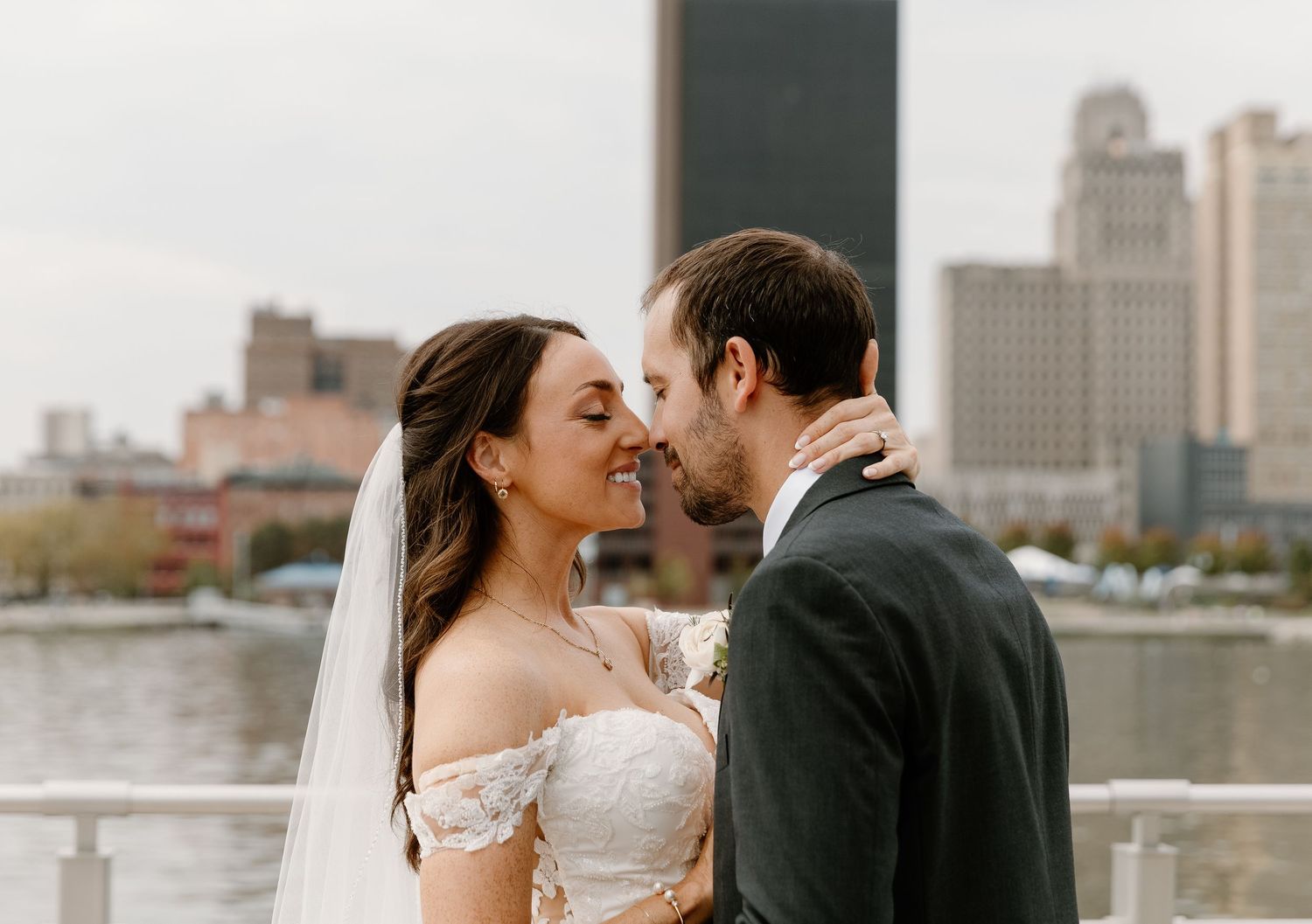 A couple shares a romantic moment against a city skyline backdrop in a series of wedding photos.