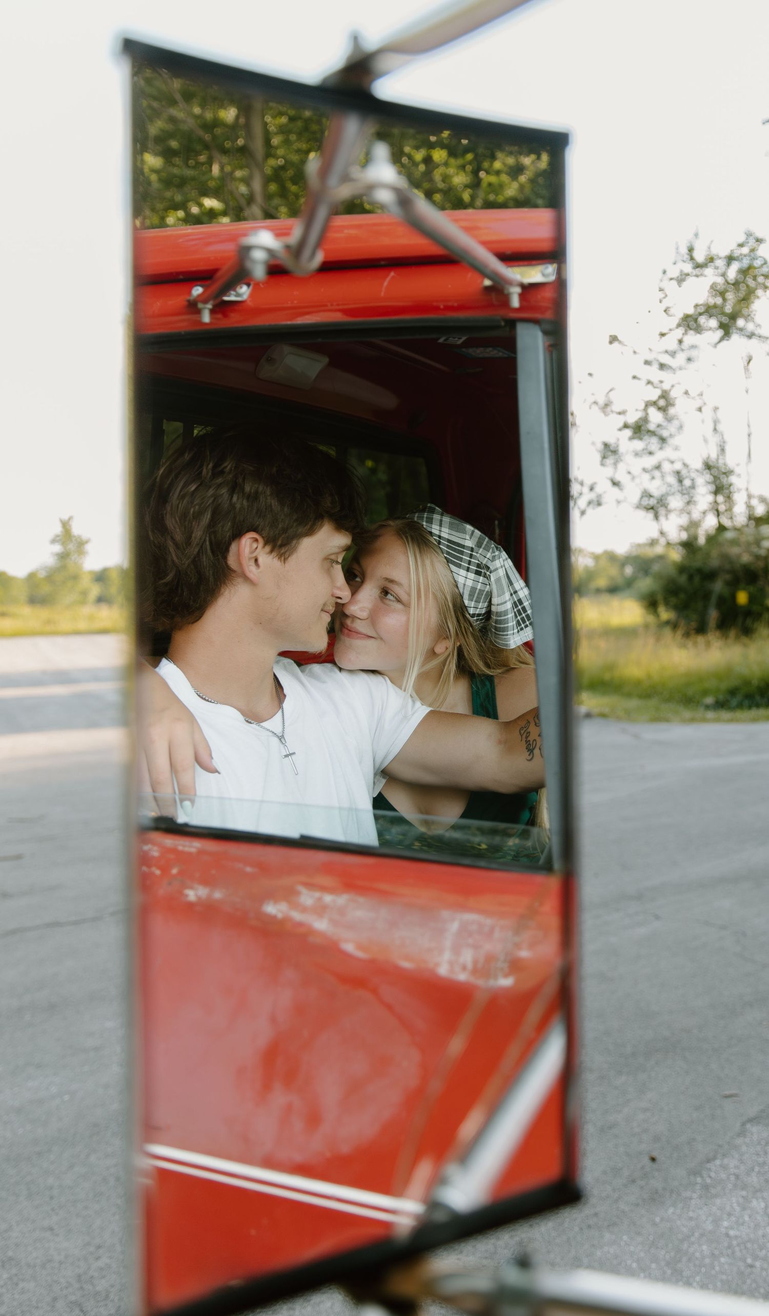 View through car window in downtown Defiance Ohio of couple sharing a romantic moment in classic red vintage automobile.
