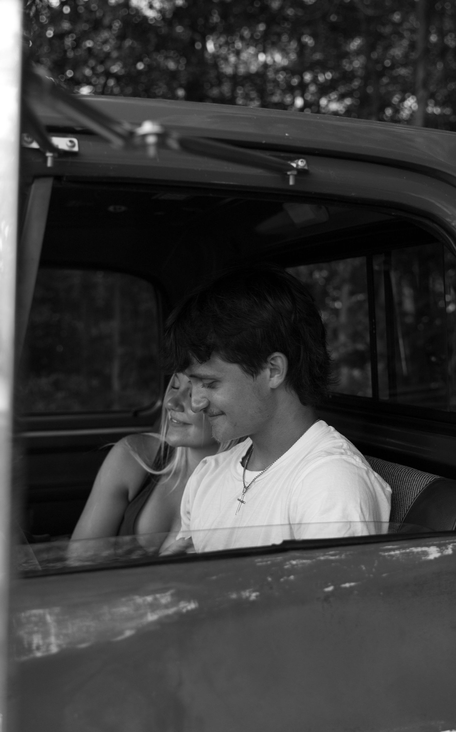 A black and white romantic photograph of an ohio couple sharing an intimate moment inside a vintage car.