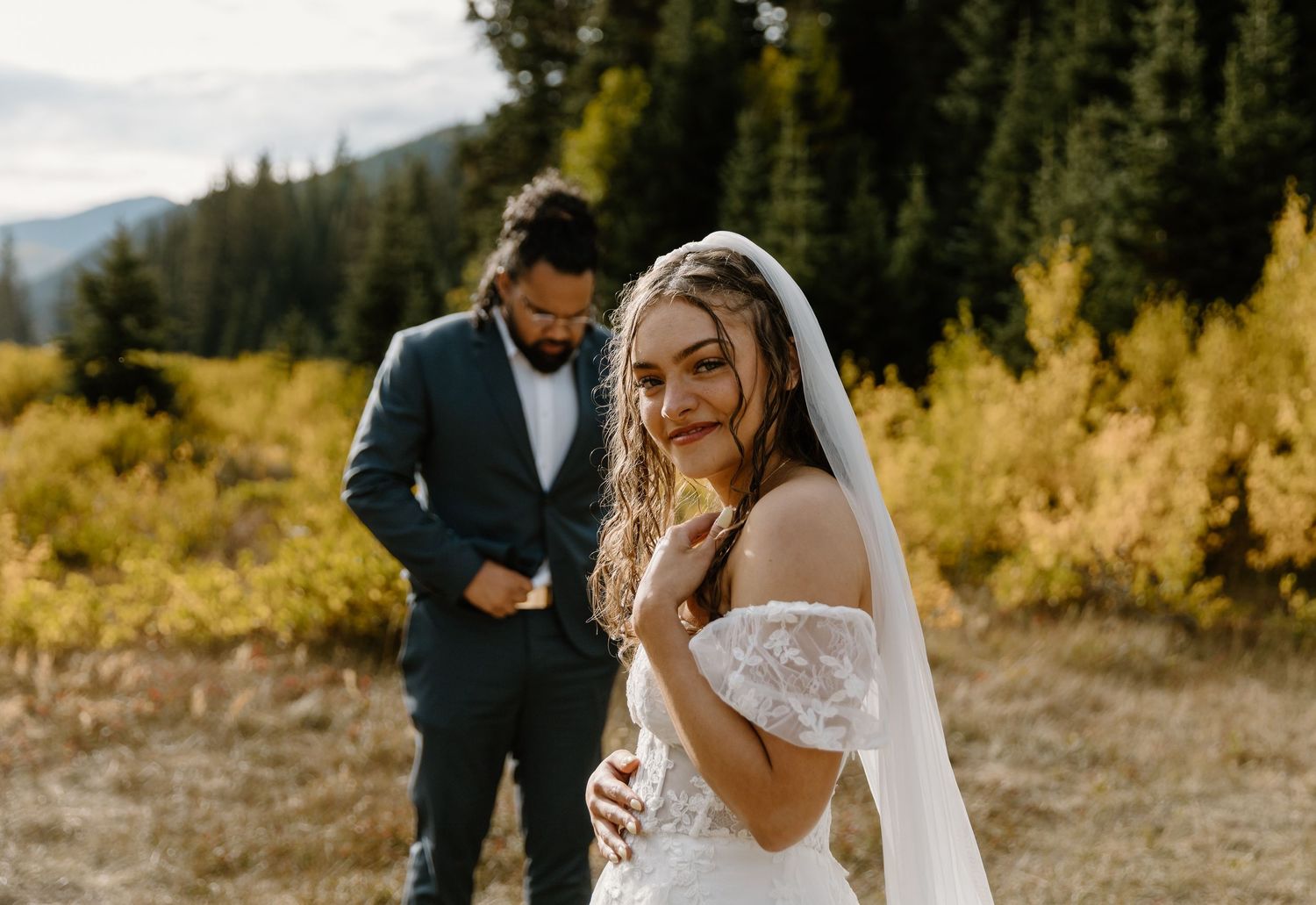 A joyful couple shares an intimate moment surrounded by golden autumn foliage in a mountainous landscape.