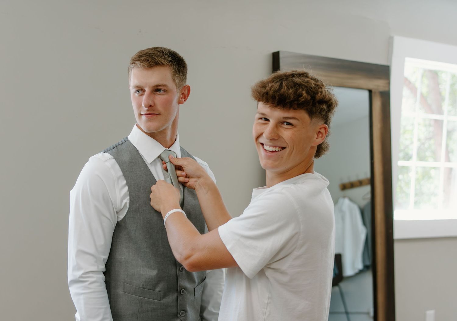 A series of photos showing groomsmen helping each other prepare and adjust their formal attire.
