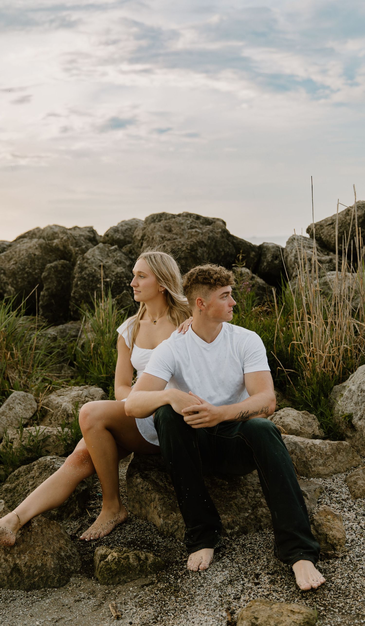 A couple sits on coastal rocks surrounded by tall grass on a cloudy day in Northwest Ohio