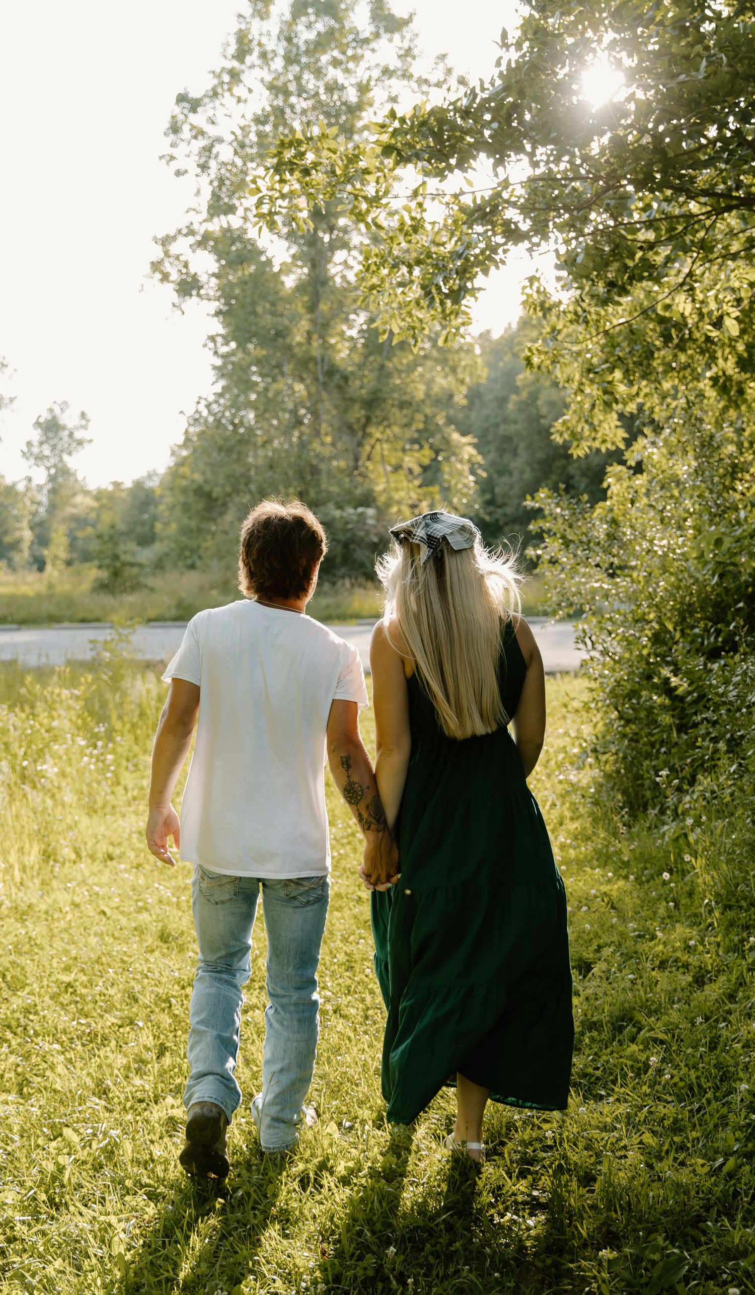 A couple walking together on a nature trail during an Ohio golden hour with trees and sunlight in the background.