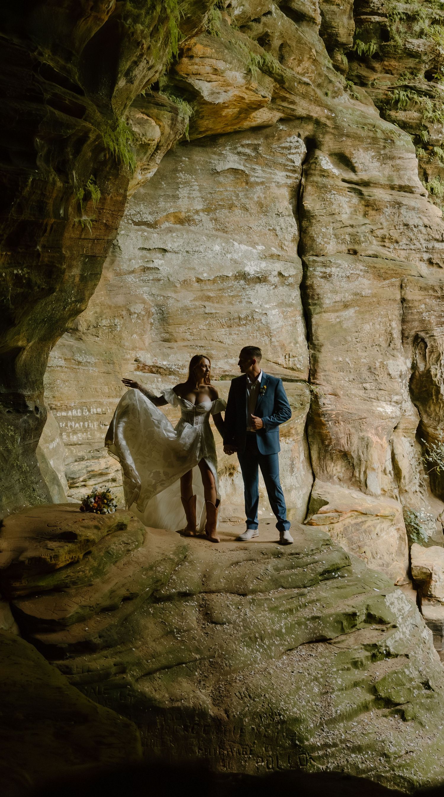 A couple explores a scenic limestone cave formation during an outdoor photo session.