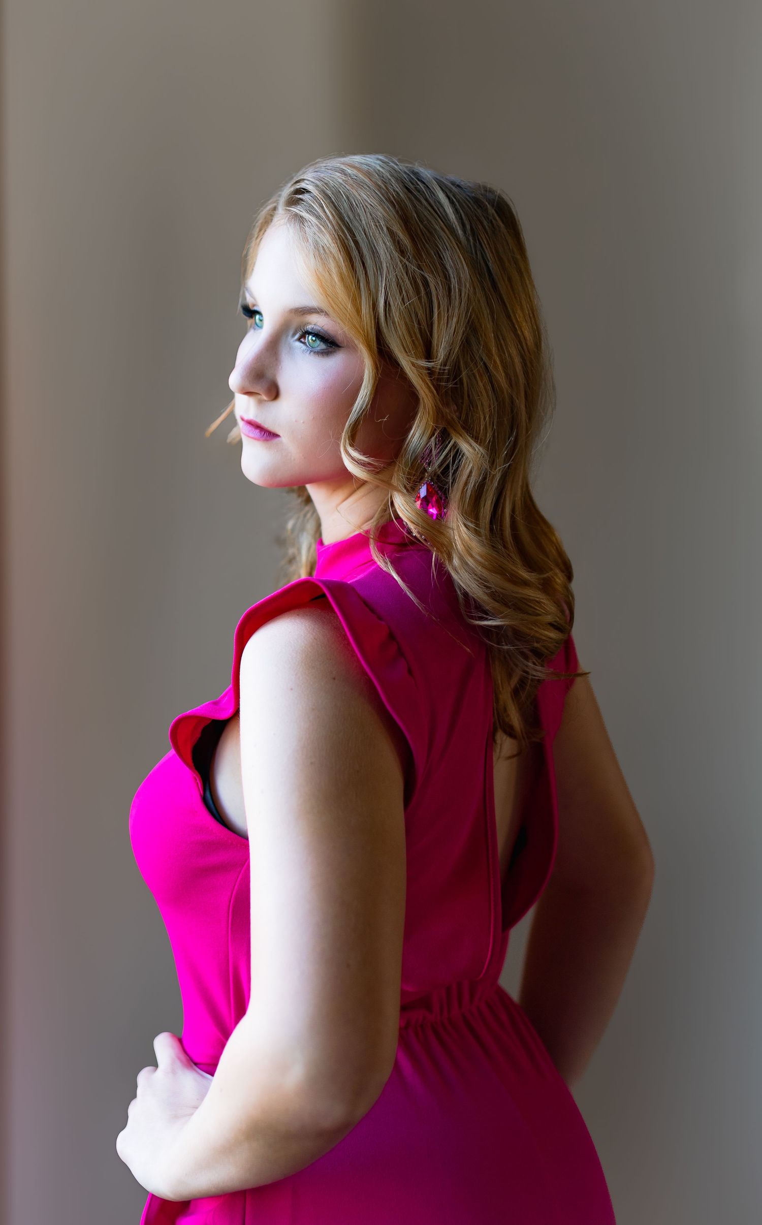 Elegant portrait in a vibrant fuchsia dress against a neutral background.
