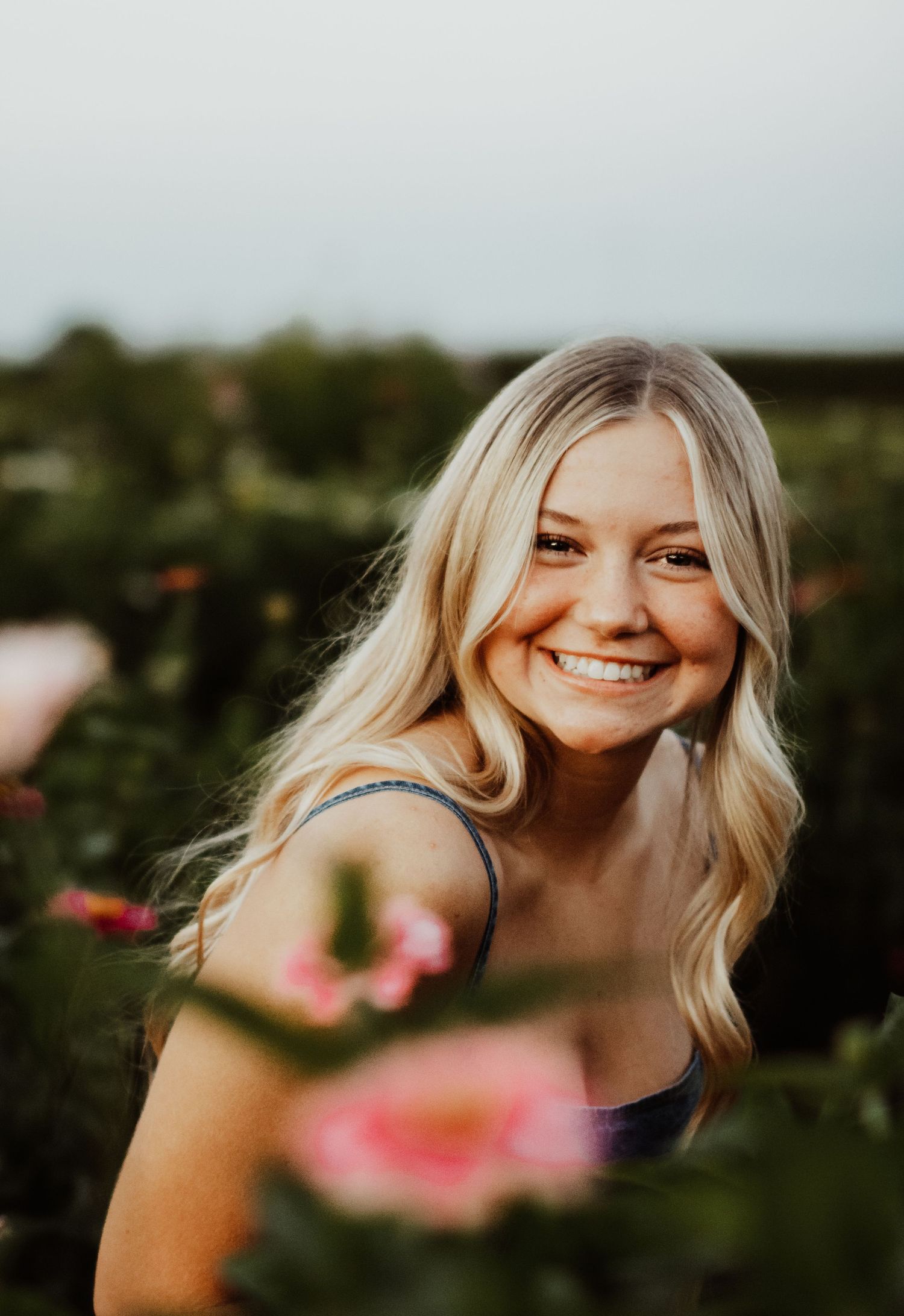 Artistic portrait through flowers capturing a joyful expression in natural light.