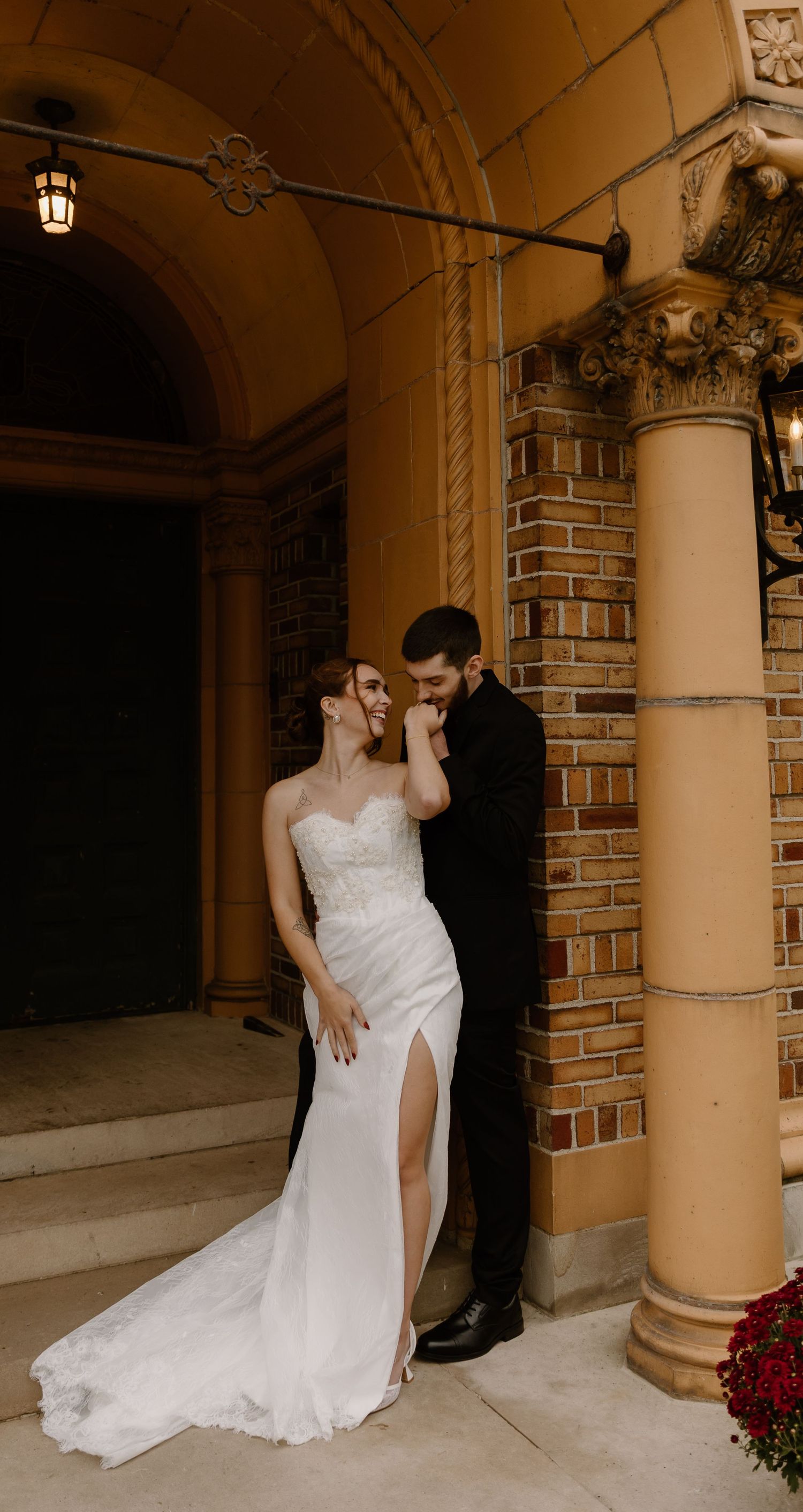 Intimate elopement couple sharing a romantic moment under brick archways with warm natural and ambient lighting, captured in a candid