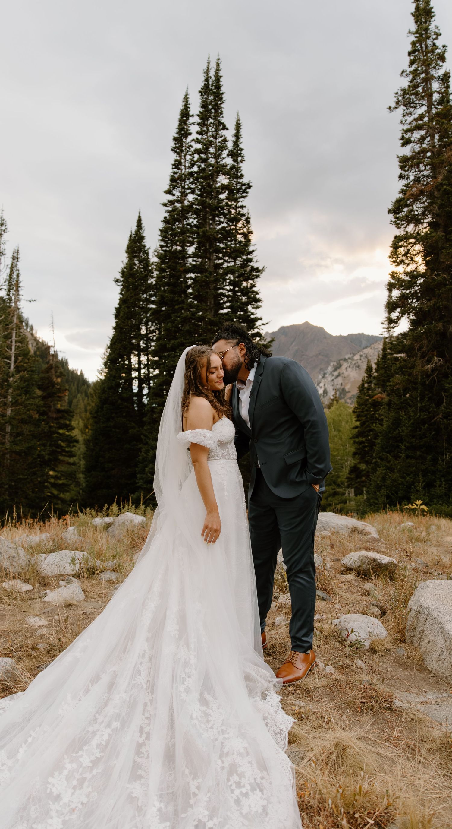 Romantic wedding portraits in a mountainous setting with pine trees and golden hour lighting.