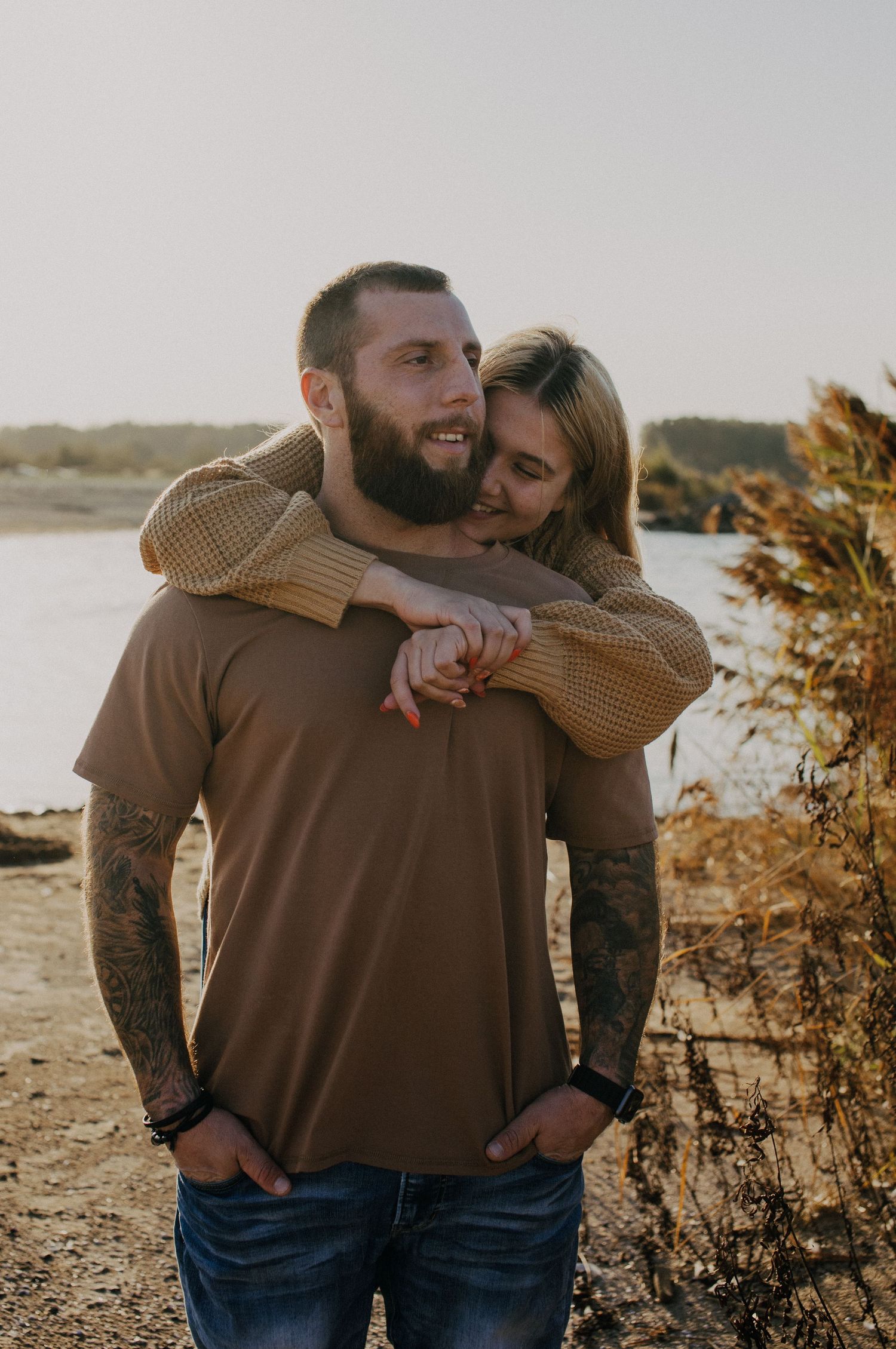 Playful piggyback ride moment captured outdoors near a lake at sunset.