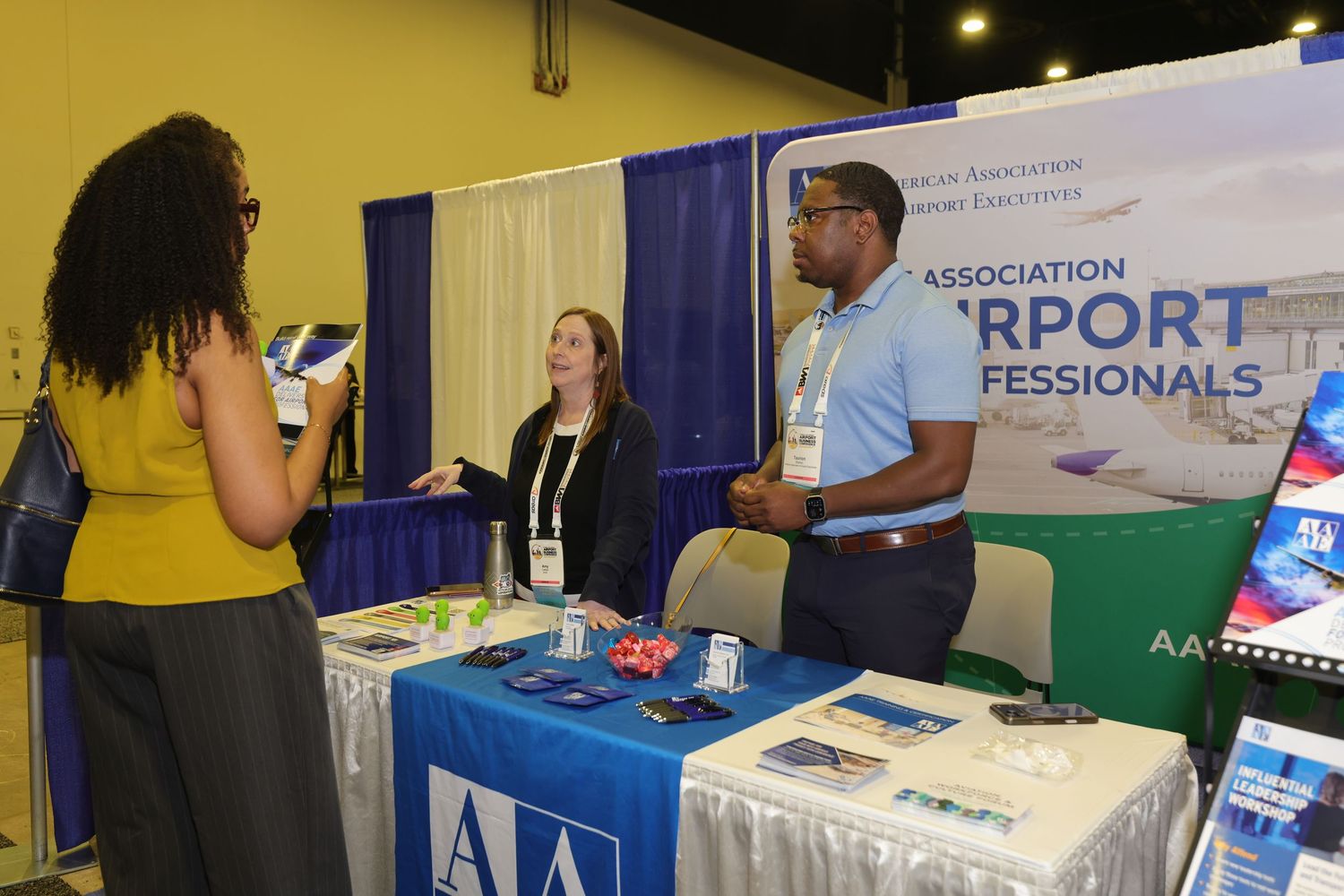 Professionals networking at an Airport Association booth during an industry conference exhibition.