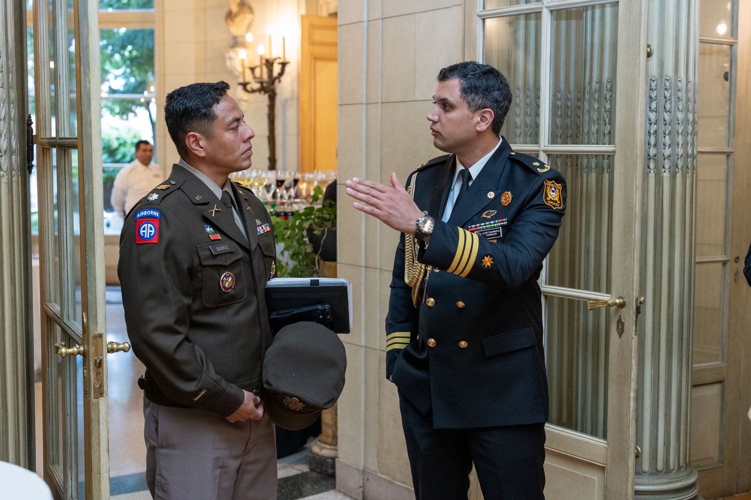 Military officer and fire chief in uniform having a discussion in an elegant building entrance.