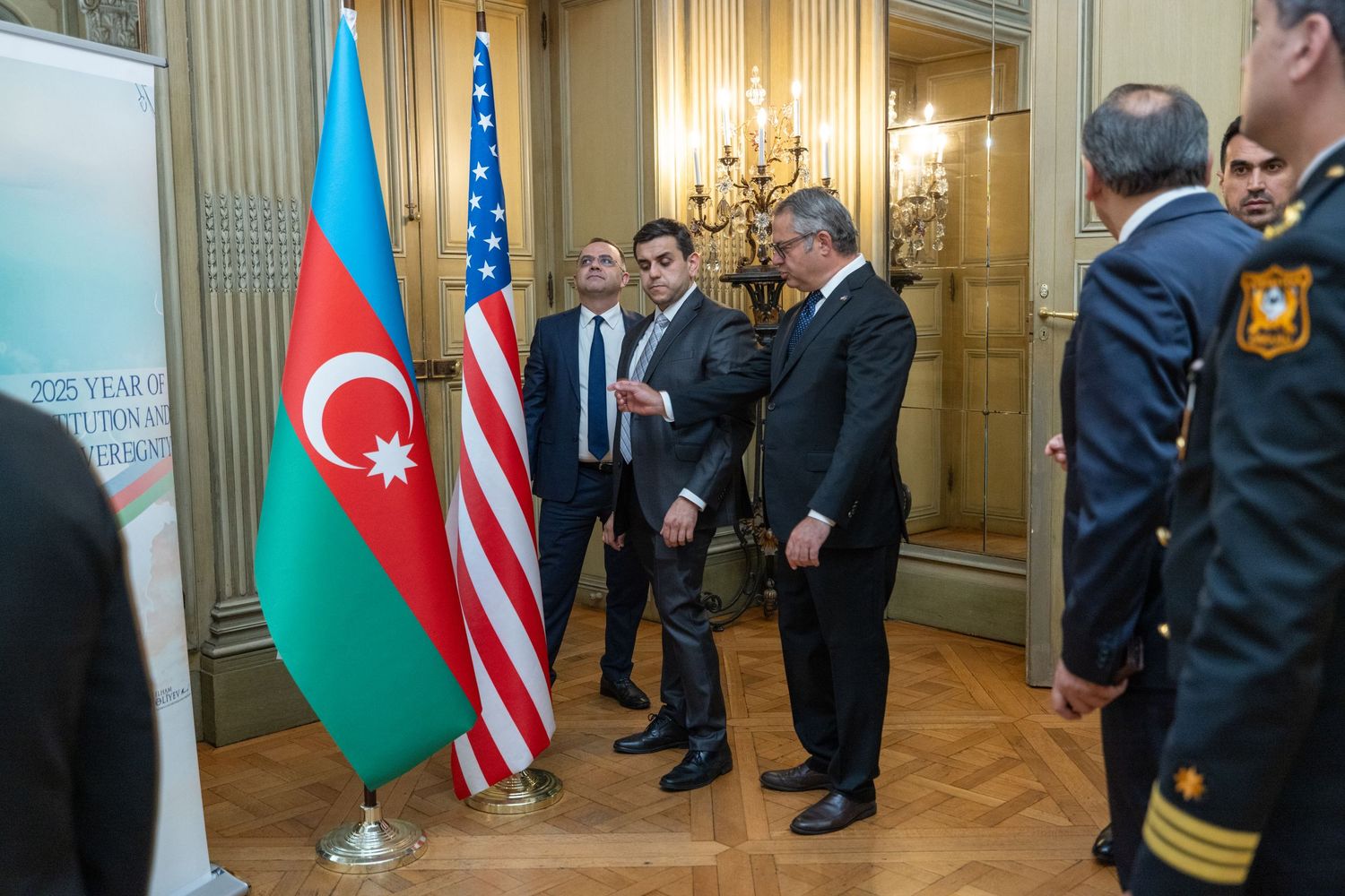 Officials gather in an ornate room with flags of Azerbaijan and the United States displayed during a diplomatic meeting.