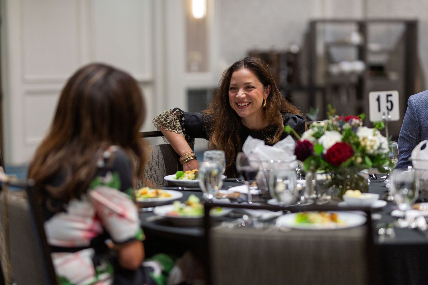 Elegant table settings with floral centerpieces at a formal dining event in a conference venue.
