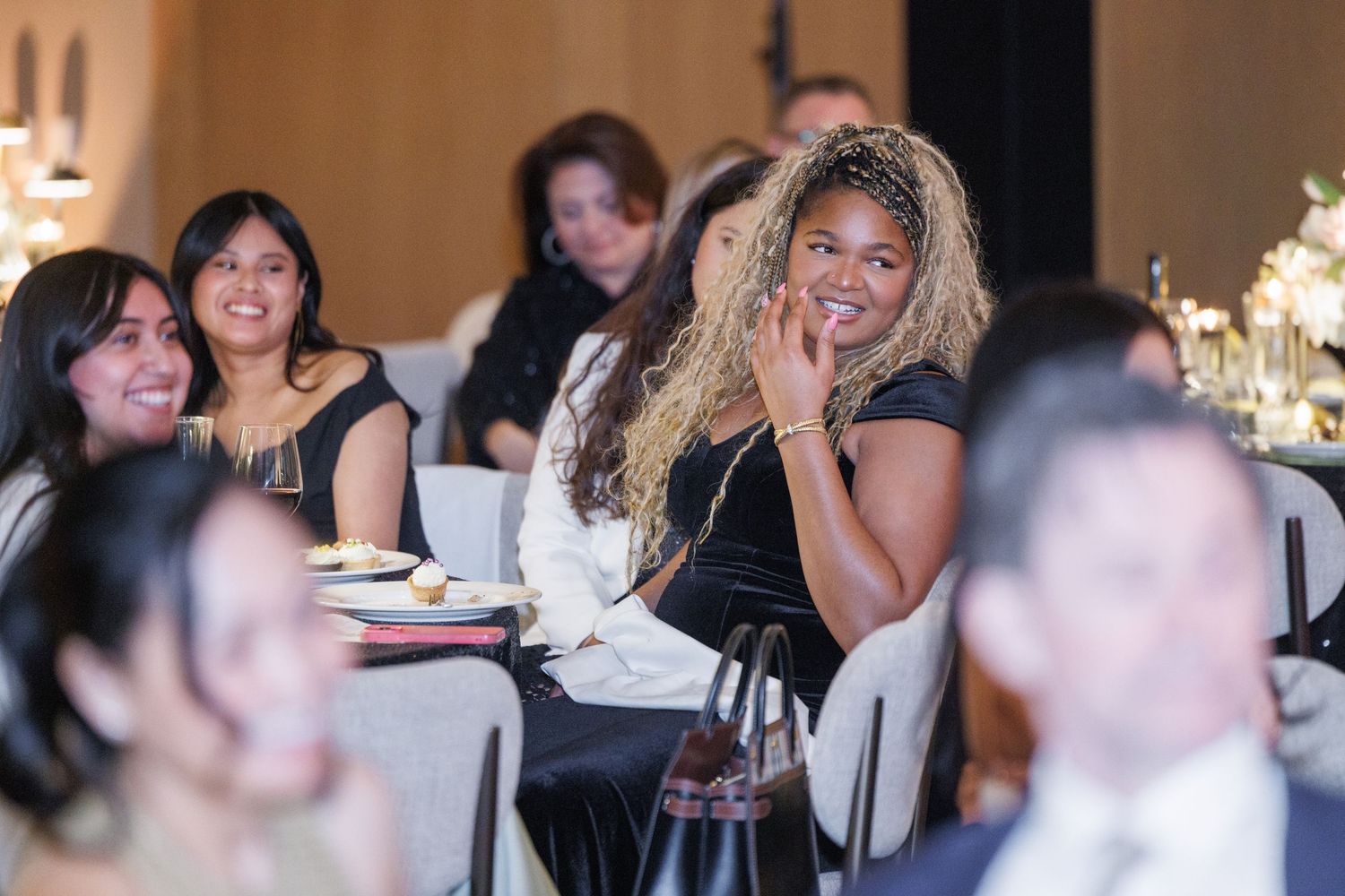 A group of people sitting at tables enjoying conversation and laughter during a social gathering.