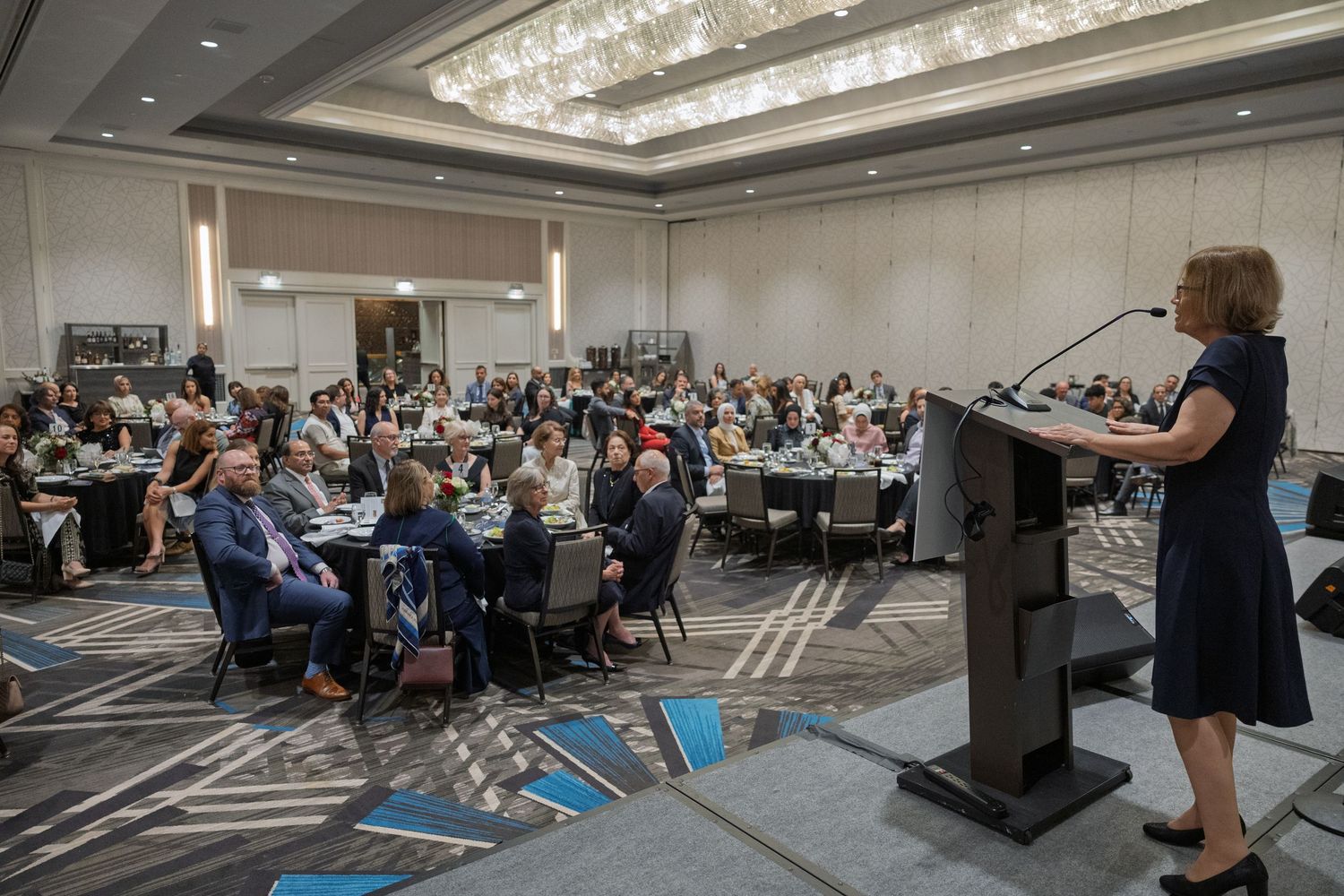 Conference attendees seated in a large hotel ballroom during a professional business presentation.
