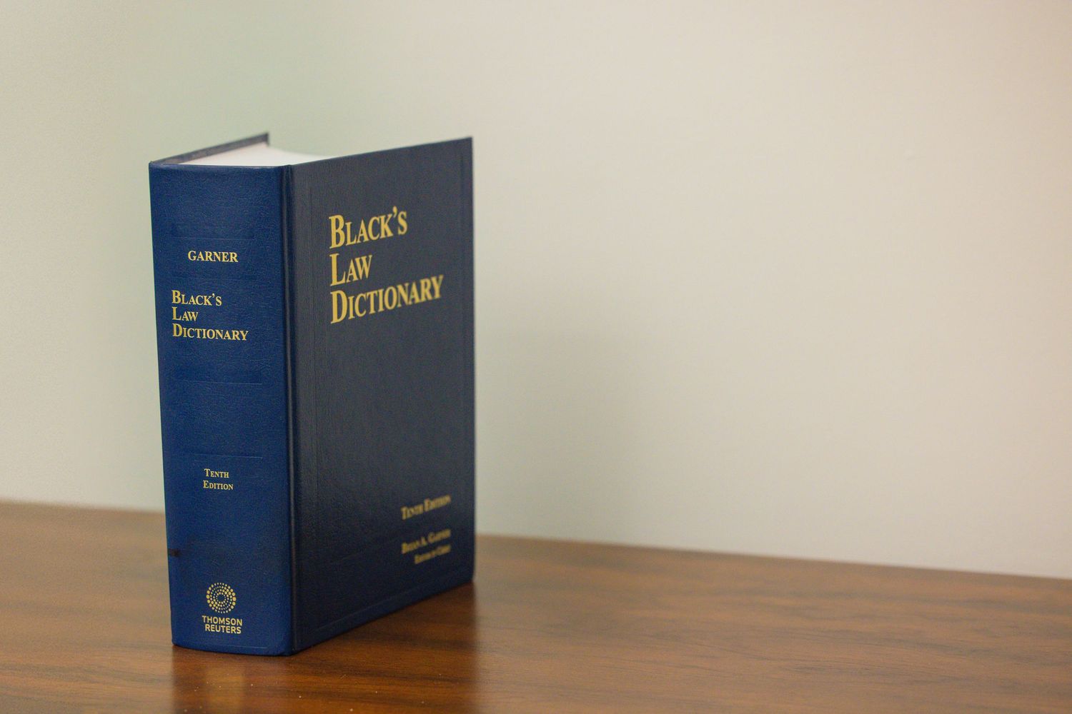Blue law book shown from multiple angles on a beige surface against a light colored wall.