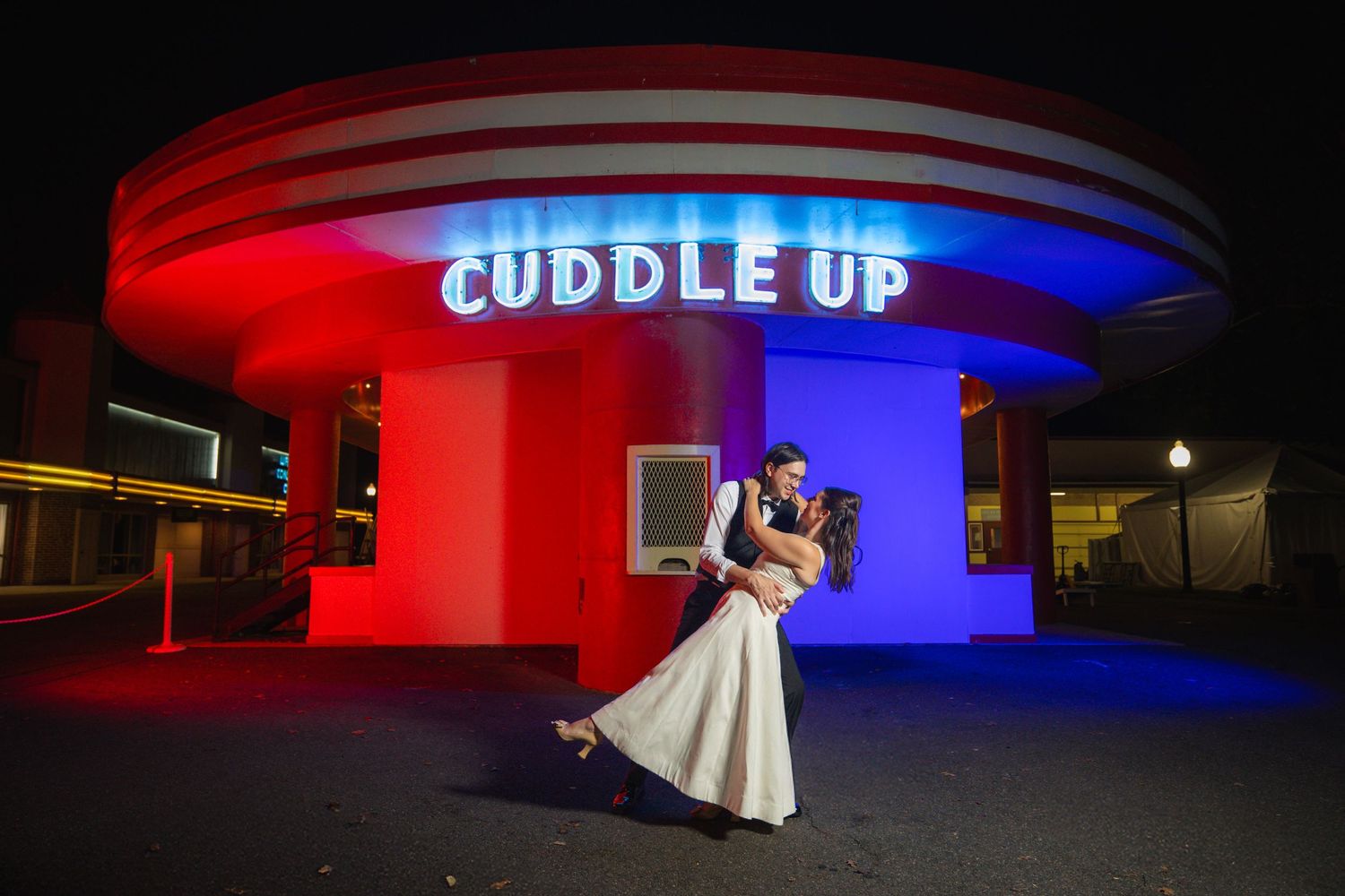 A modern building exterior illuminated with vibrant red and blue lighting at night creating a dramatic architectural display.