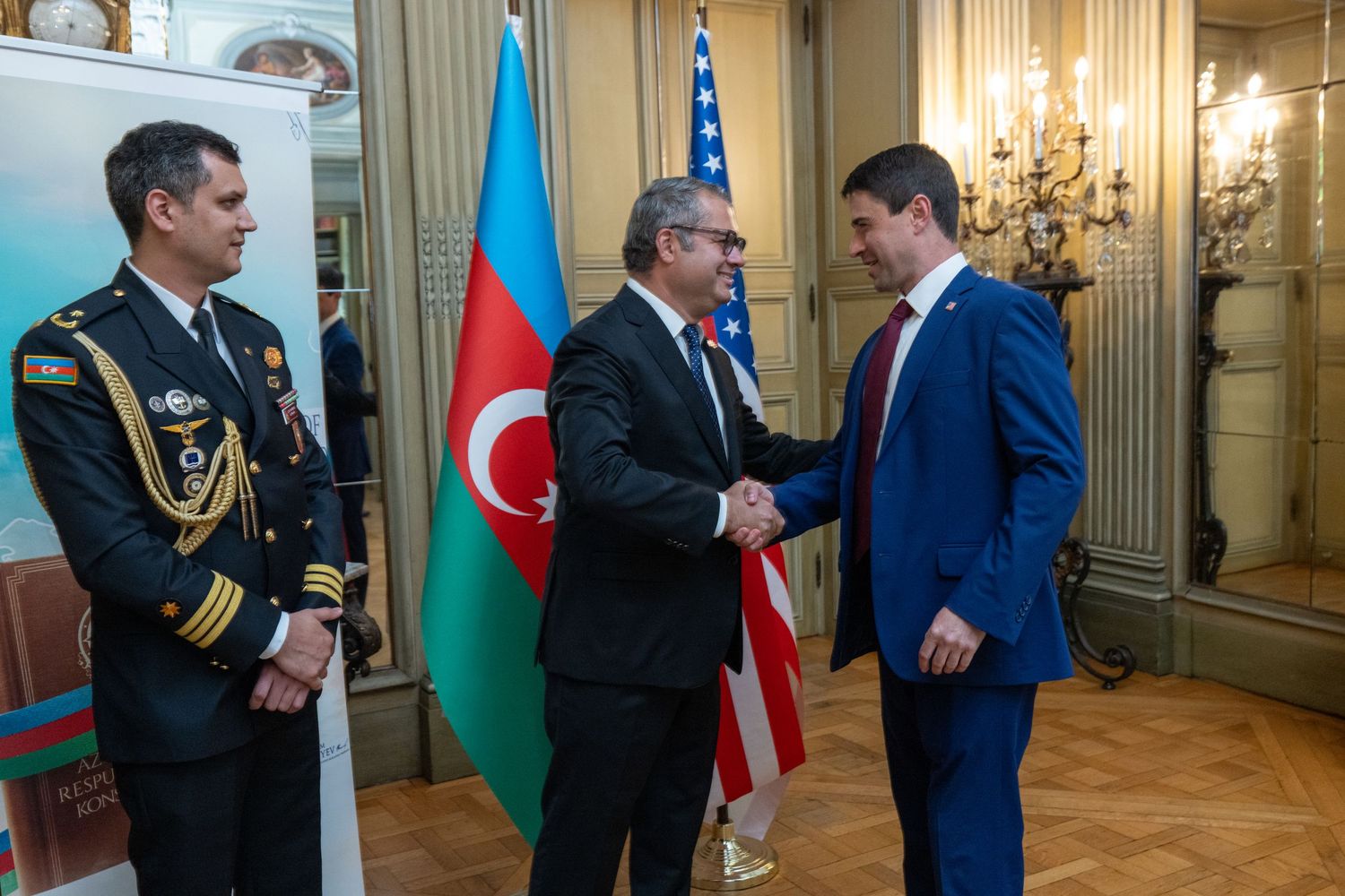 Officials and diplomats gather in an ornate room with flags of Azerbaijan and Turkey displayed during a formal event.