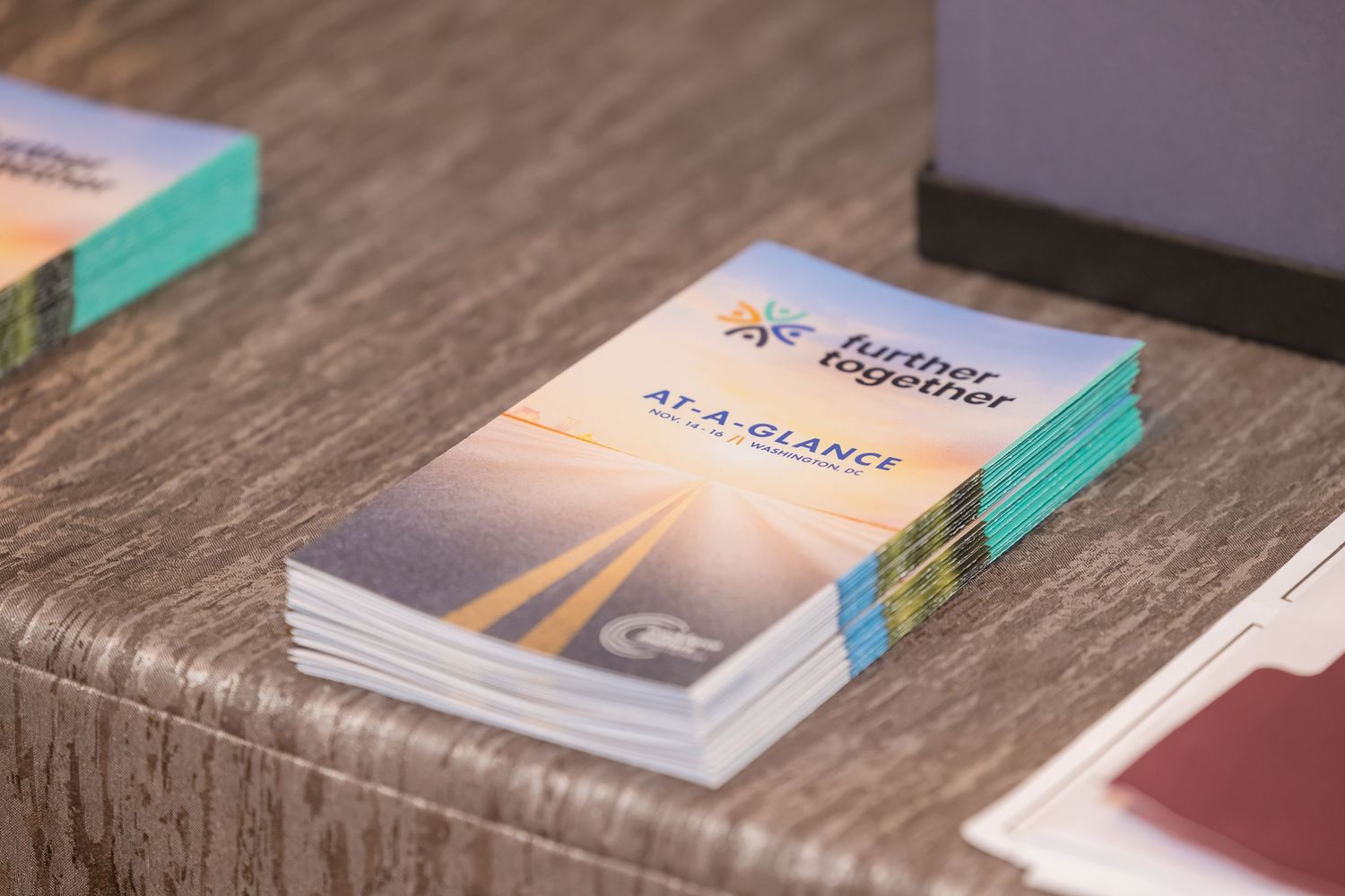 Stack of hardcover books arranged on a rustic wooden table with teal accents visible in the background.