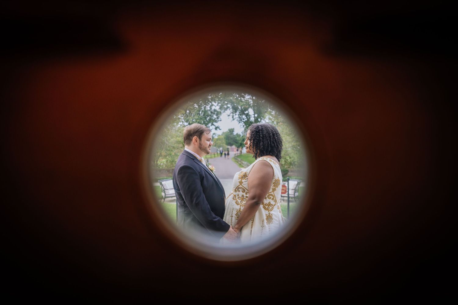 A couple in formal wedding attire shares a tender moment during their outdoor celebration.