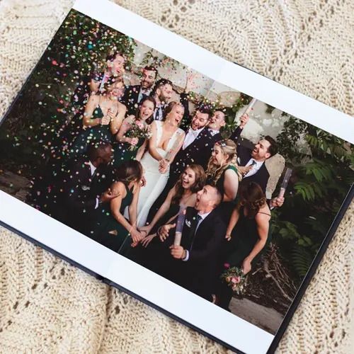 Wedding party celebrating with colorful confetti in an outdoor garden setting.