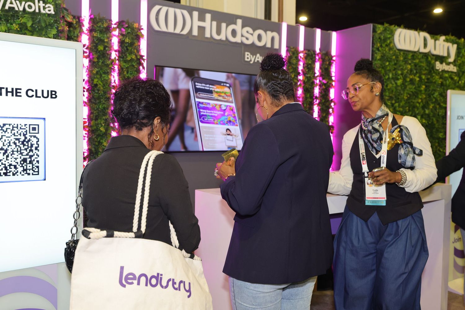 People networking at Hudson booth during a trade show, with a Lendistry tote bag visible in the foreground.
