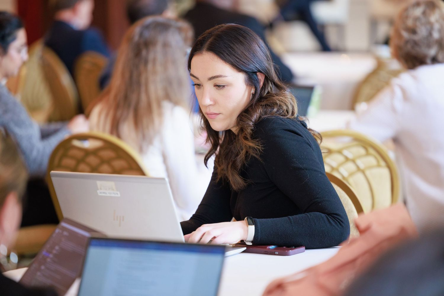 Students taking notes and studying together at tables in a classroom or library setting.