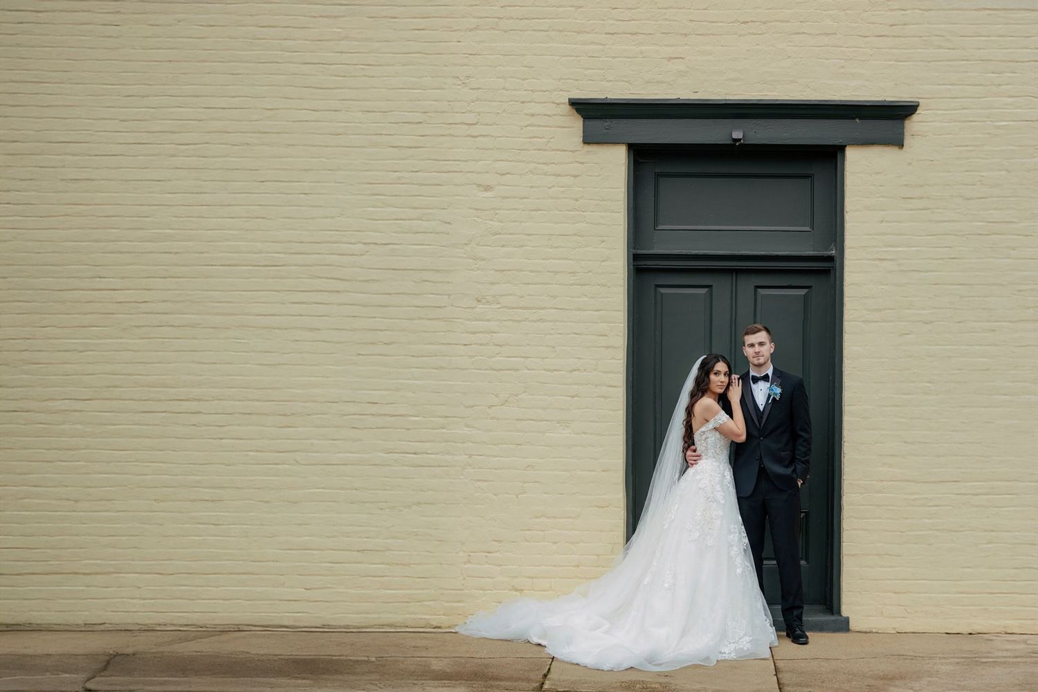 A series of wedding photos showing a couple posing against a cream colored wall with dark framed windows.