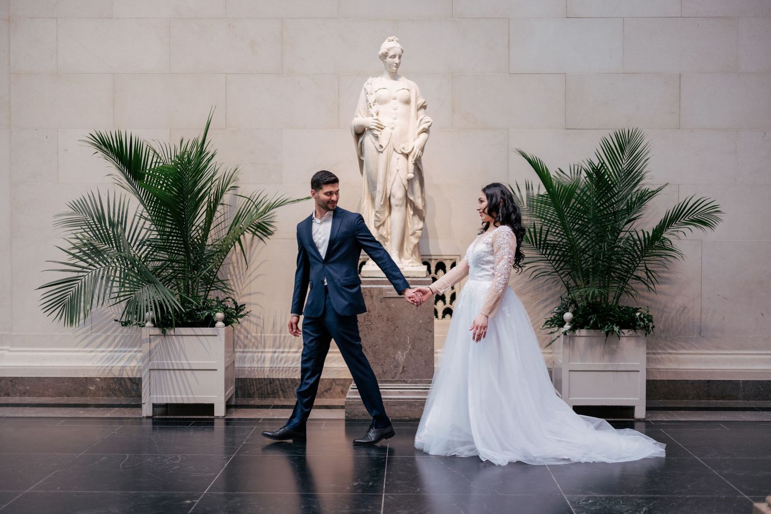 Wedding couple shares playful dance moves in a sequence of photos at an elegant stone venue with potted palms.