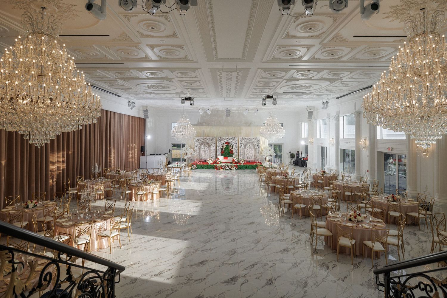 Elegant ballroom with crystal chandeliers, marble floors and gold chiavari chairs set for a luxurious wedding reception.