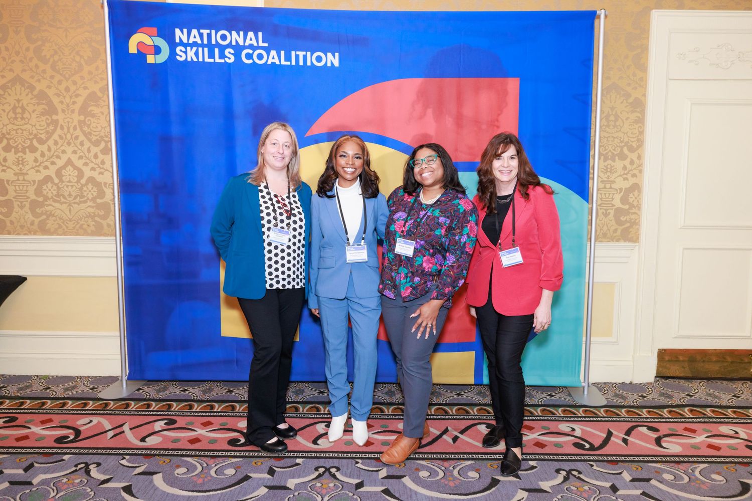 Group of people standing in front of a National Skills Coalition banner at a professional conference event.