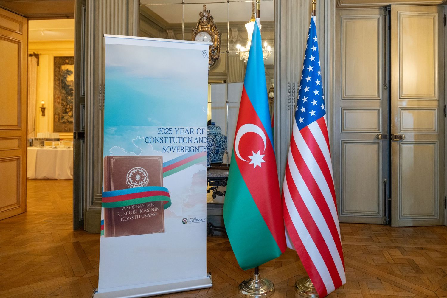 Display banner stands next to Azerbaijani and American flags at a formal diplomatic event.