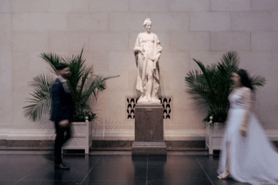 A series of blurry motion photographs showing ghostly figures moving through a hallway with palm plants and statues.
