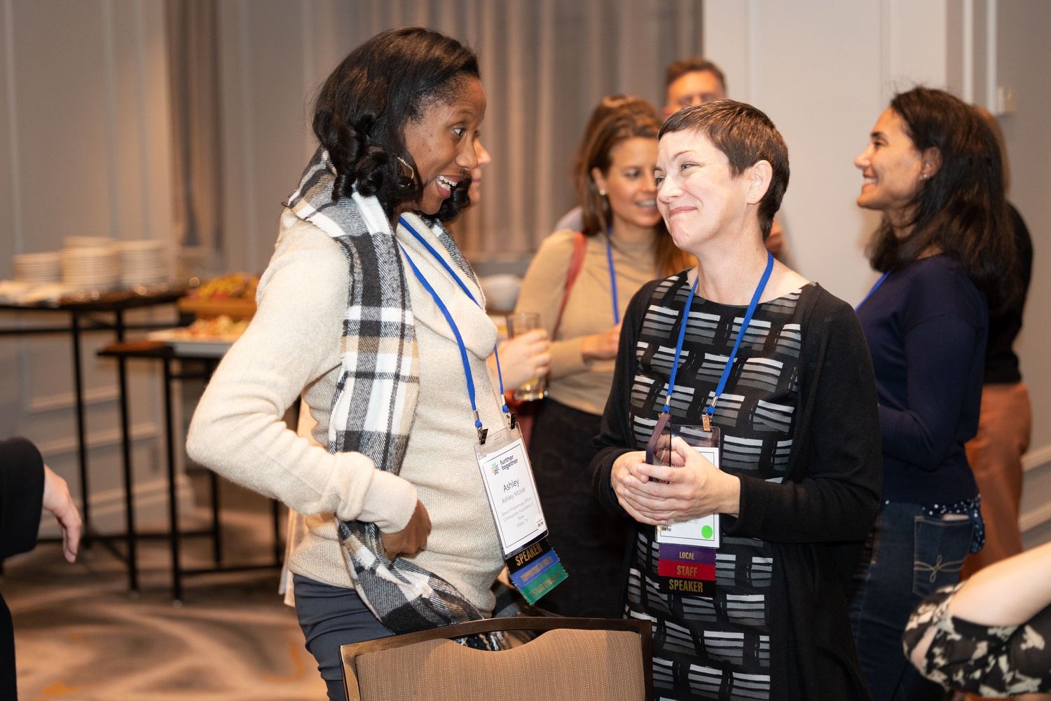 People engaged in animated conversation during a professional networking event at an indoor venue.
