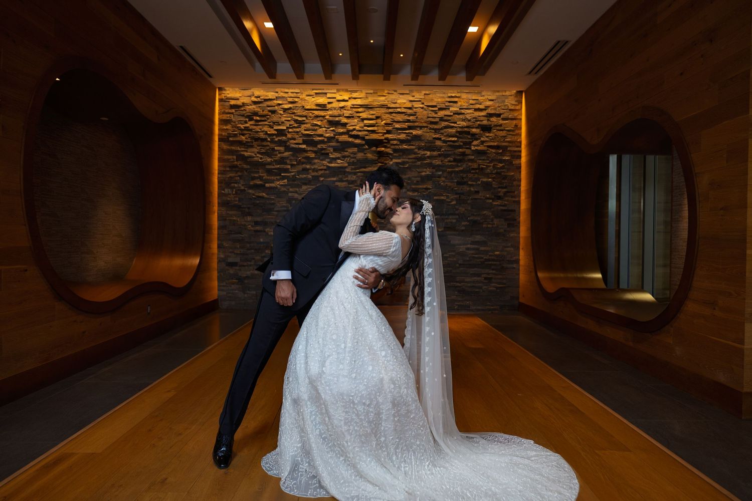 A couple shares an intimate moment in an elegantly lit hotel hallway with textured golden walls.