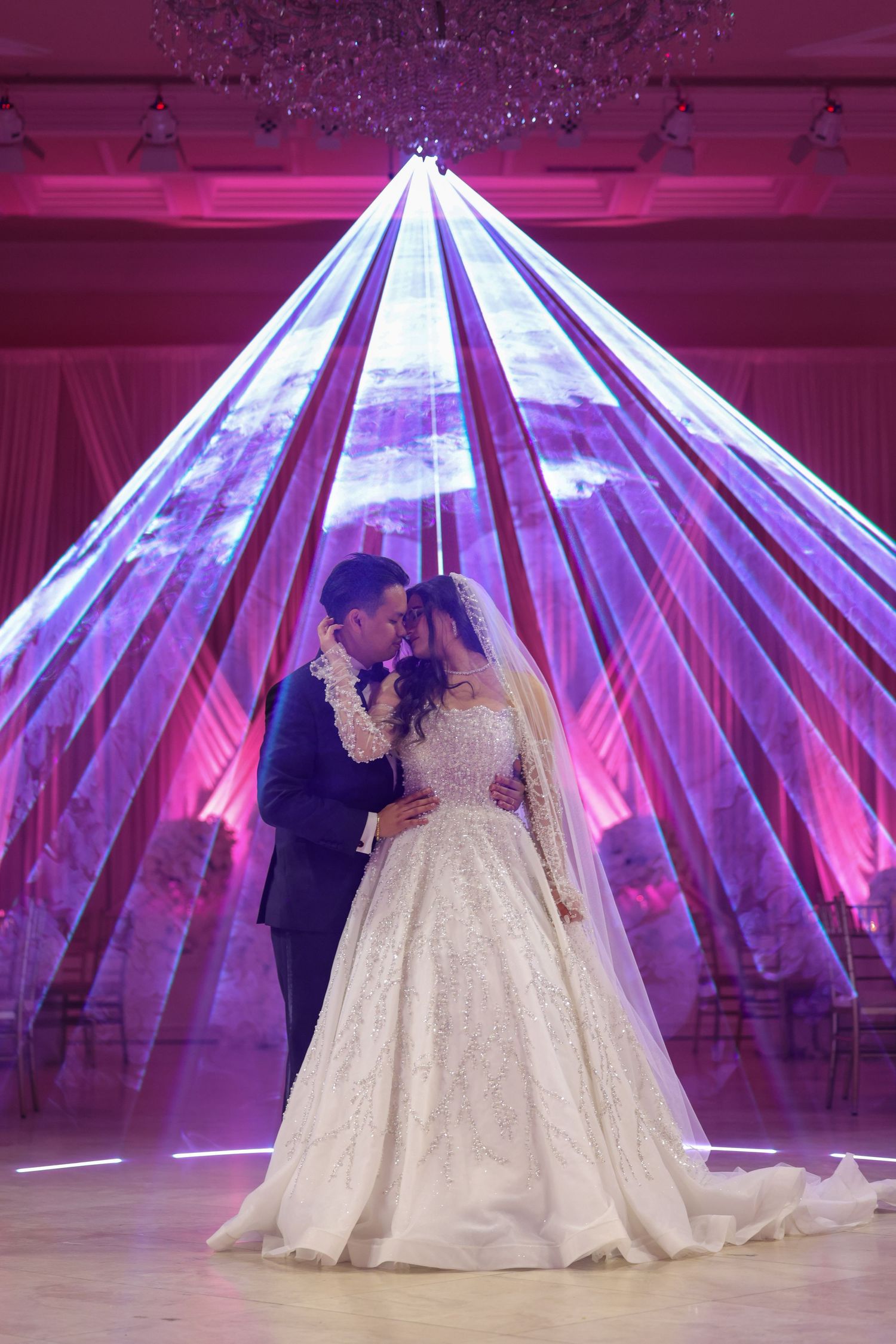 A couple shares their first dance under a dramatic illuminated geometric dome structure at their wedding reception.