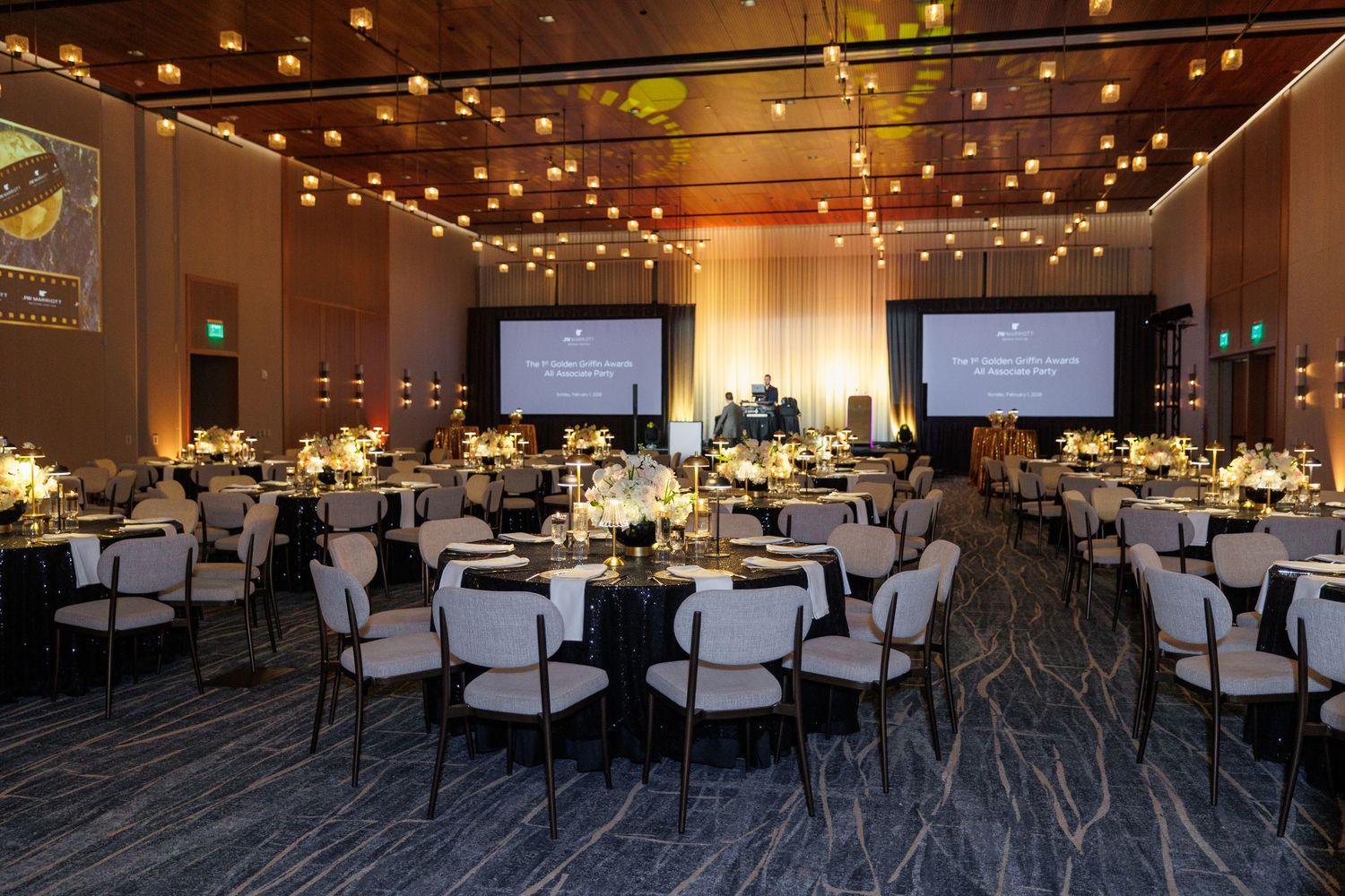 Large event space with string lights overhead and rows of white chairs set up for a conference or presentation.