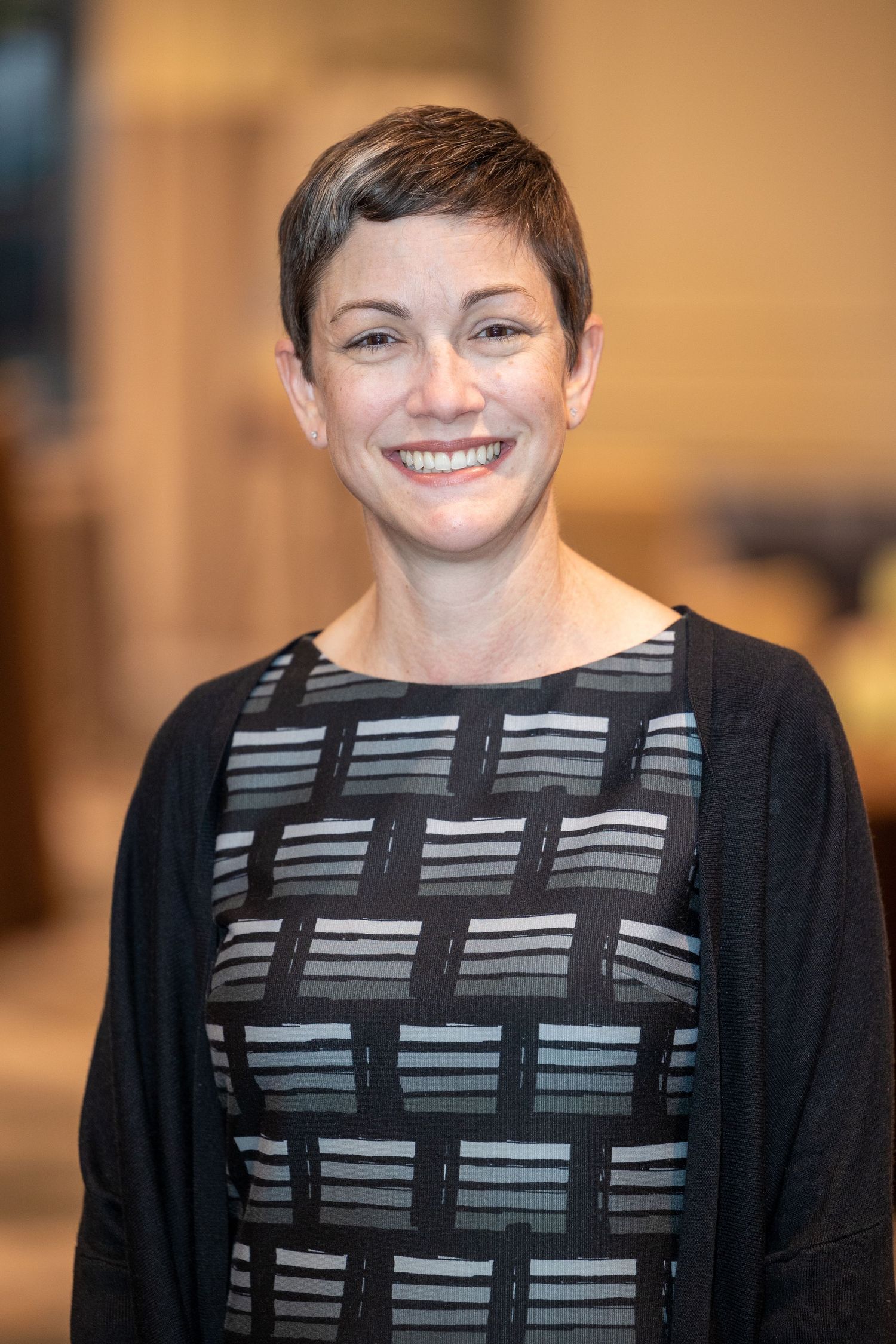 A person wearing a black and gray geometric patterned sweater smiles warmly in a series of connected photos.