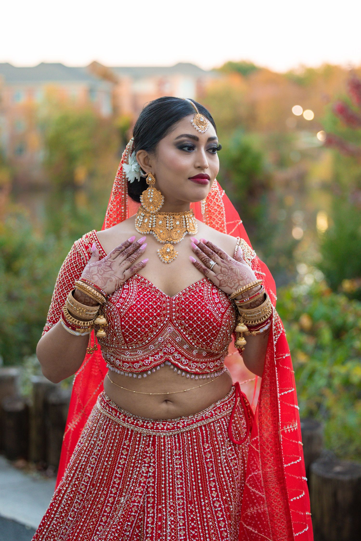 Traditional Indian bridal attire featuring a red sequined lehenga with intricate beadwork and matching jewelry.